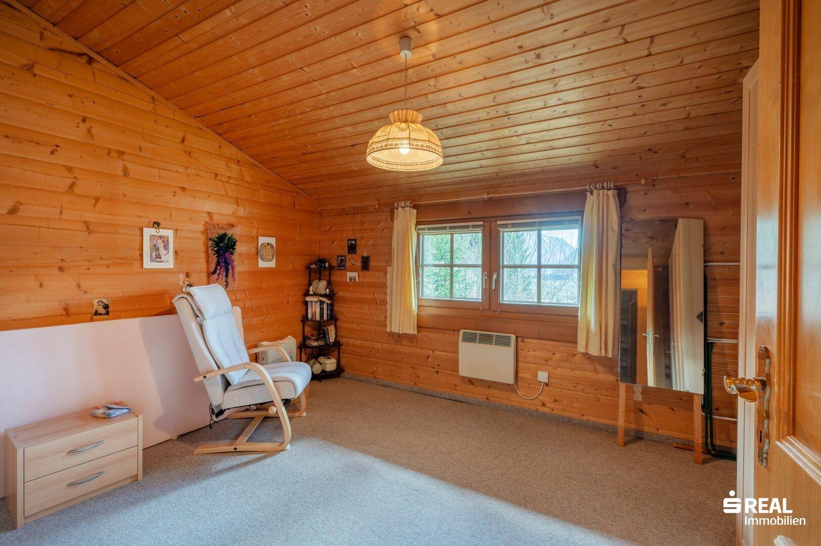 Geräumiges Schlafzimmer mit Holzvertäfelung, Teppichboden und Fenster mit Bergblick.