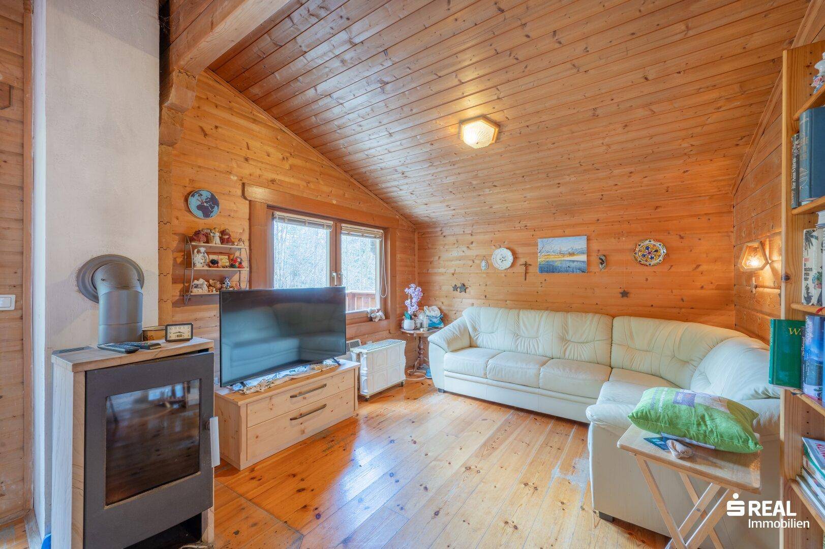 Rustikales Wohnzimmer mit Holzvertäfelung, Holzboden und Kaminofen für gemütliche Abende.