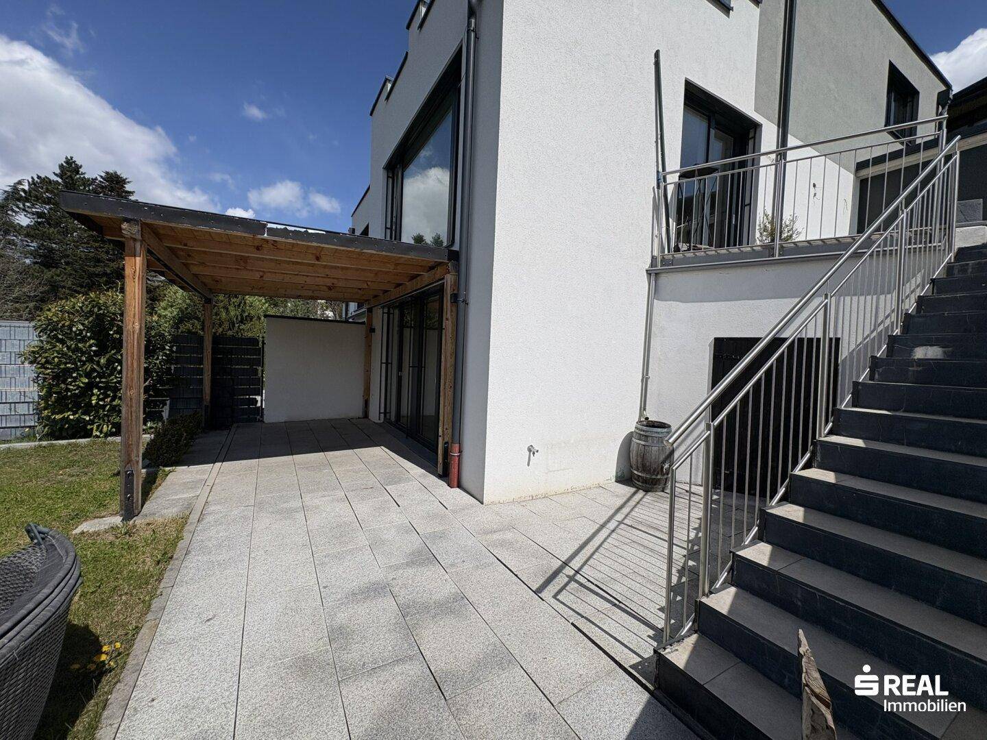 Geräumige Terrasse mit Granitplatten und Zugang zum Garten über eine Außentreppe.