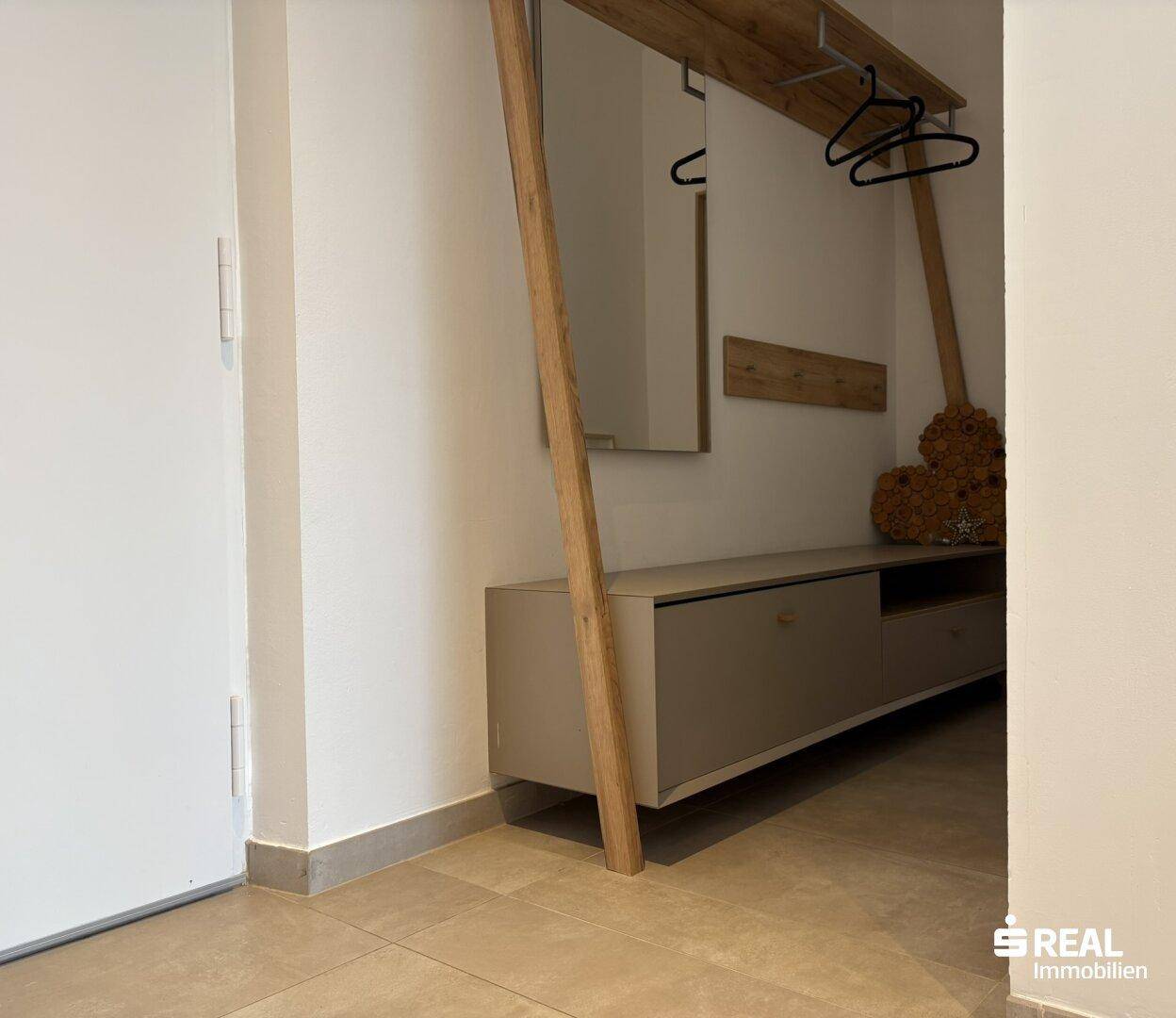 Eingangsbereich mit moderner Garderobe, Spiegel und praktischer Sitzgelegenheit.