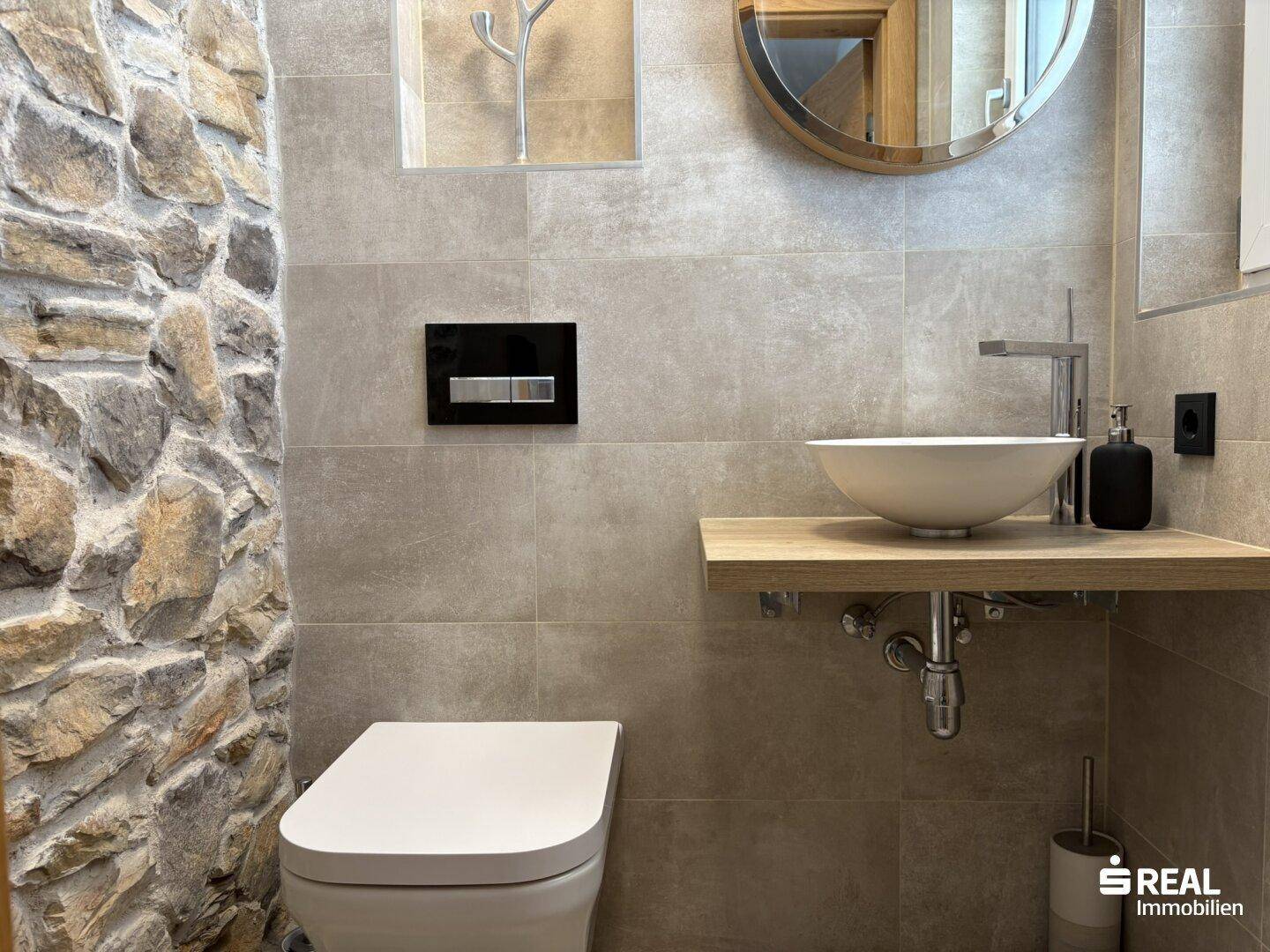 Modernes Gäste-WC mit Natursteinwand, Aufsatzwaschbecken und Wand-WC.