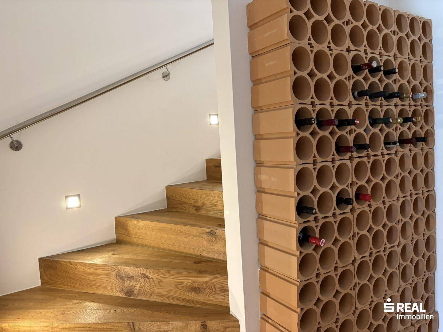 Praktisches Weinregal neben der Holztreppe für die Lagerung von Weinflaschen.