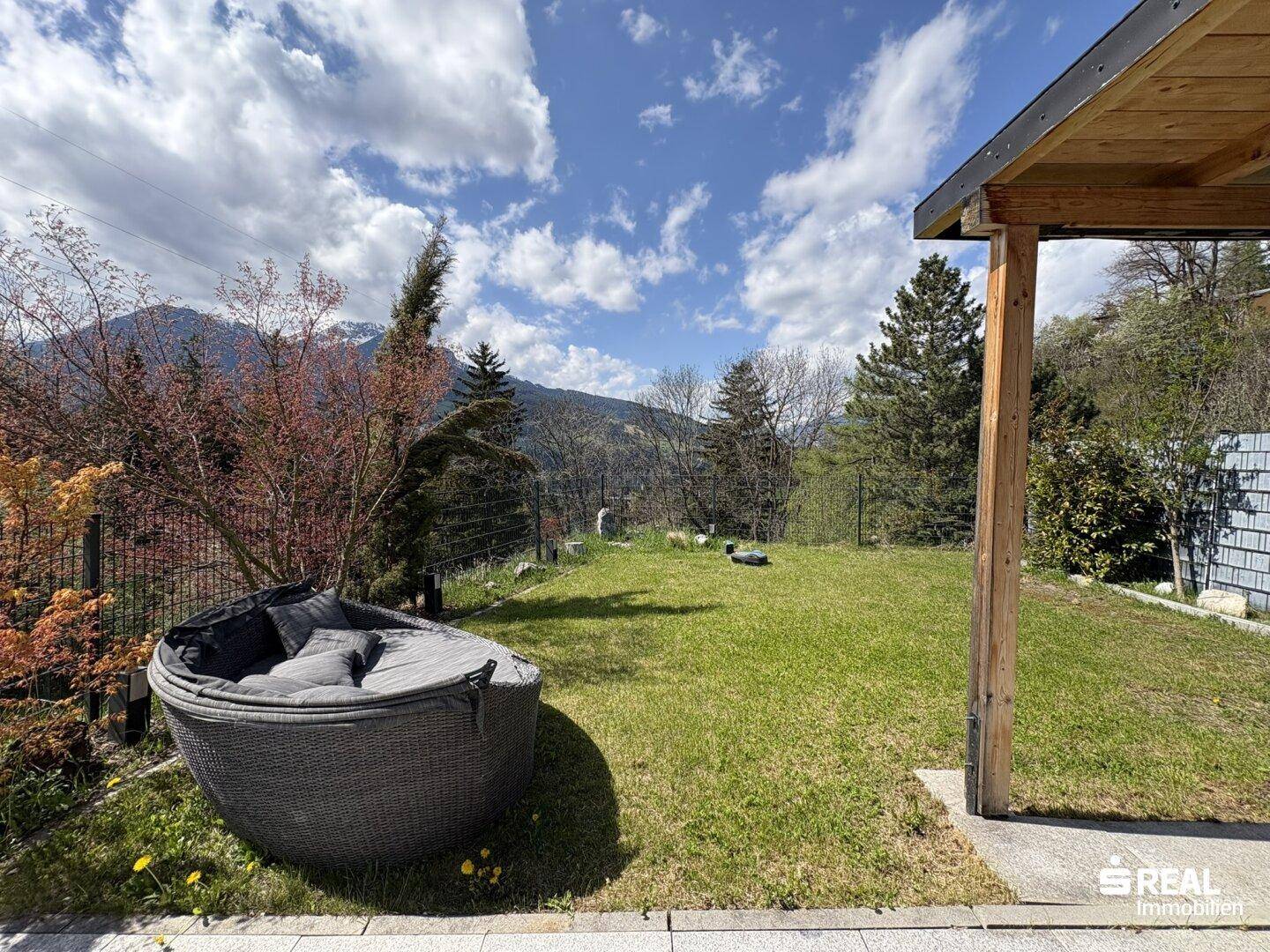 Grüner Gartenbereich mit gemütlicher Lounge-Ecke und Blick auf die Berge.