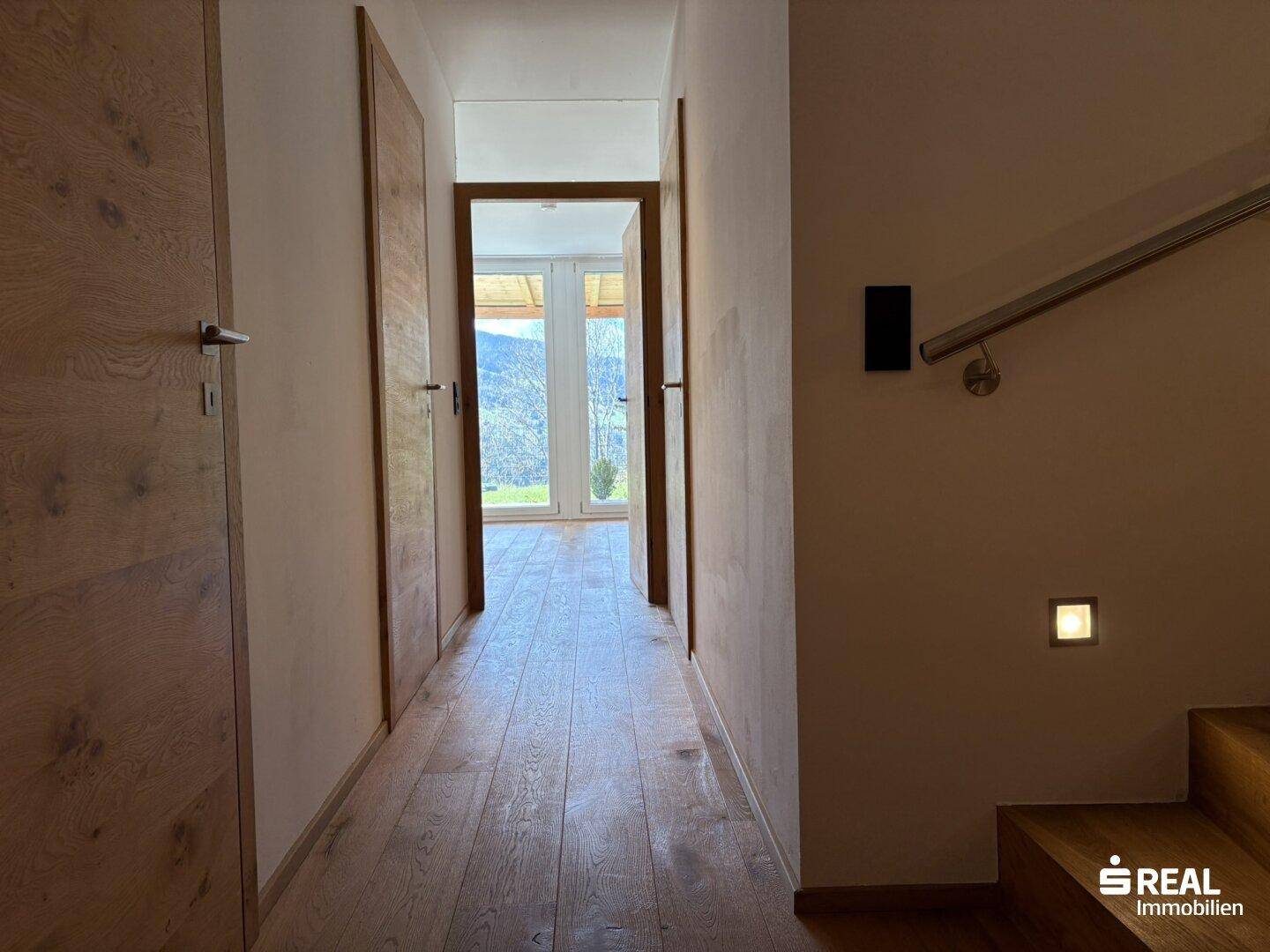 Heller Flur mit Holzboden und Zugang zu weiteren Räumen mit Bergblick.