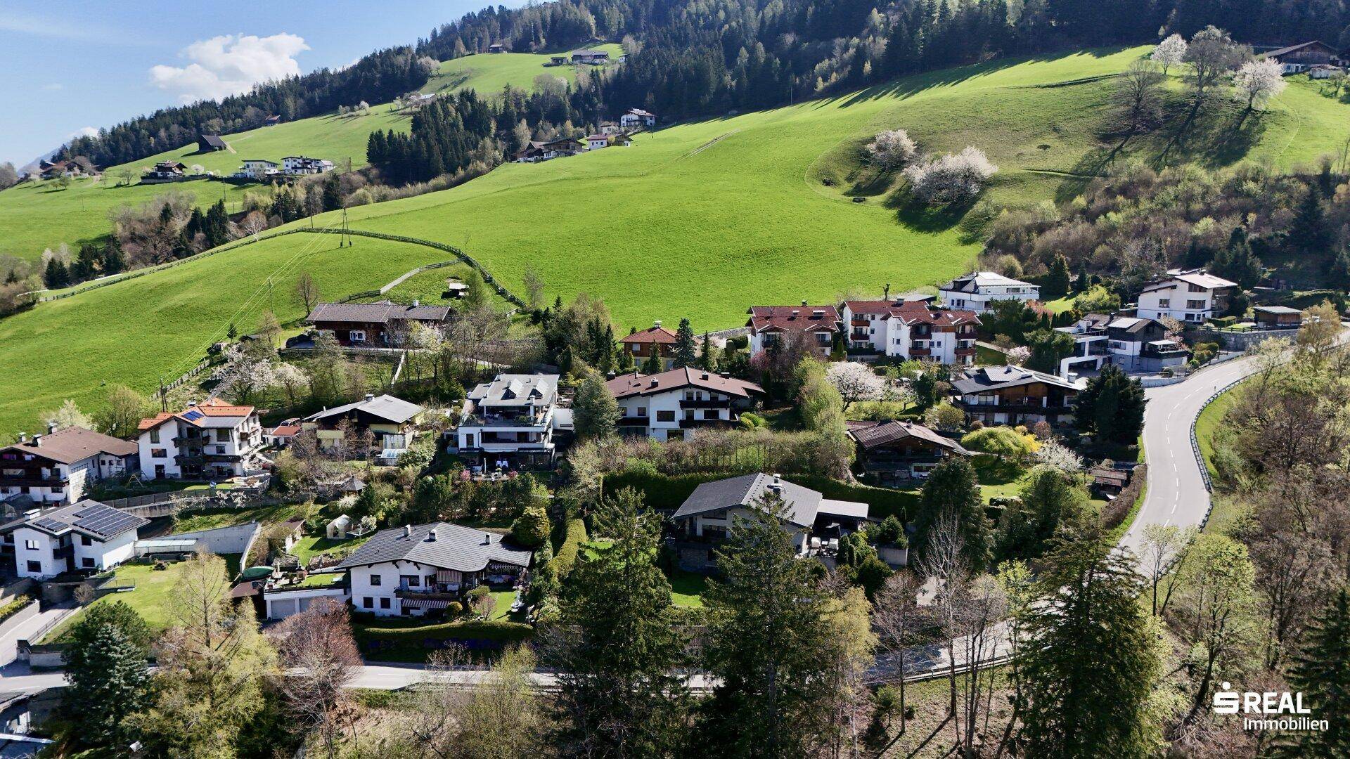 Weitläufige Wohnsiedlung in einer grünen Hügellandschaft mit vielen Einfamilienhäusern.