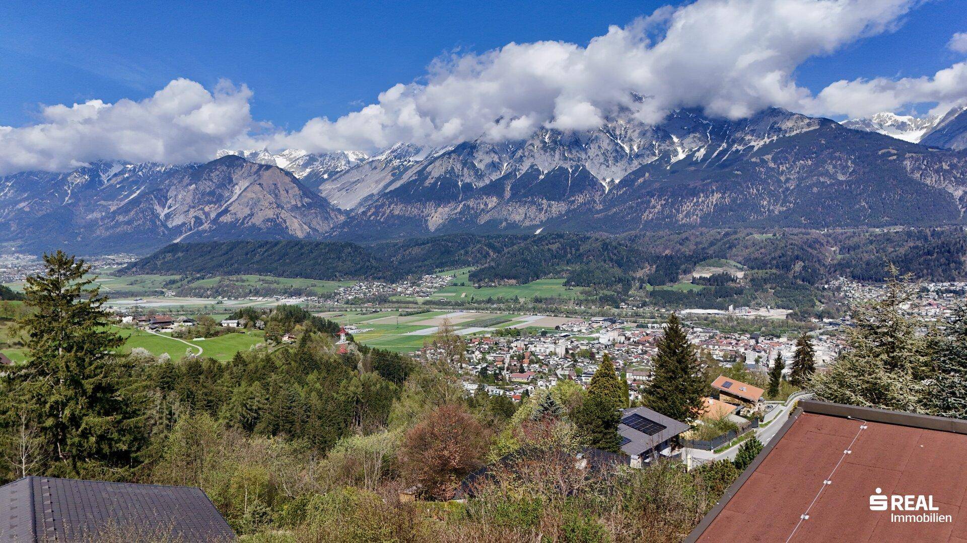 Atemberaubender Panoramablick auf schneebedeckte Berge und ein weites Tal mit Siedlungen.