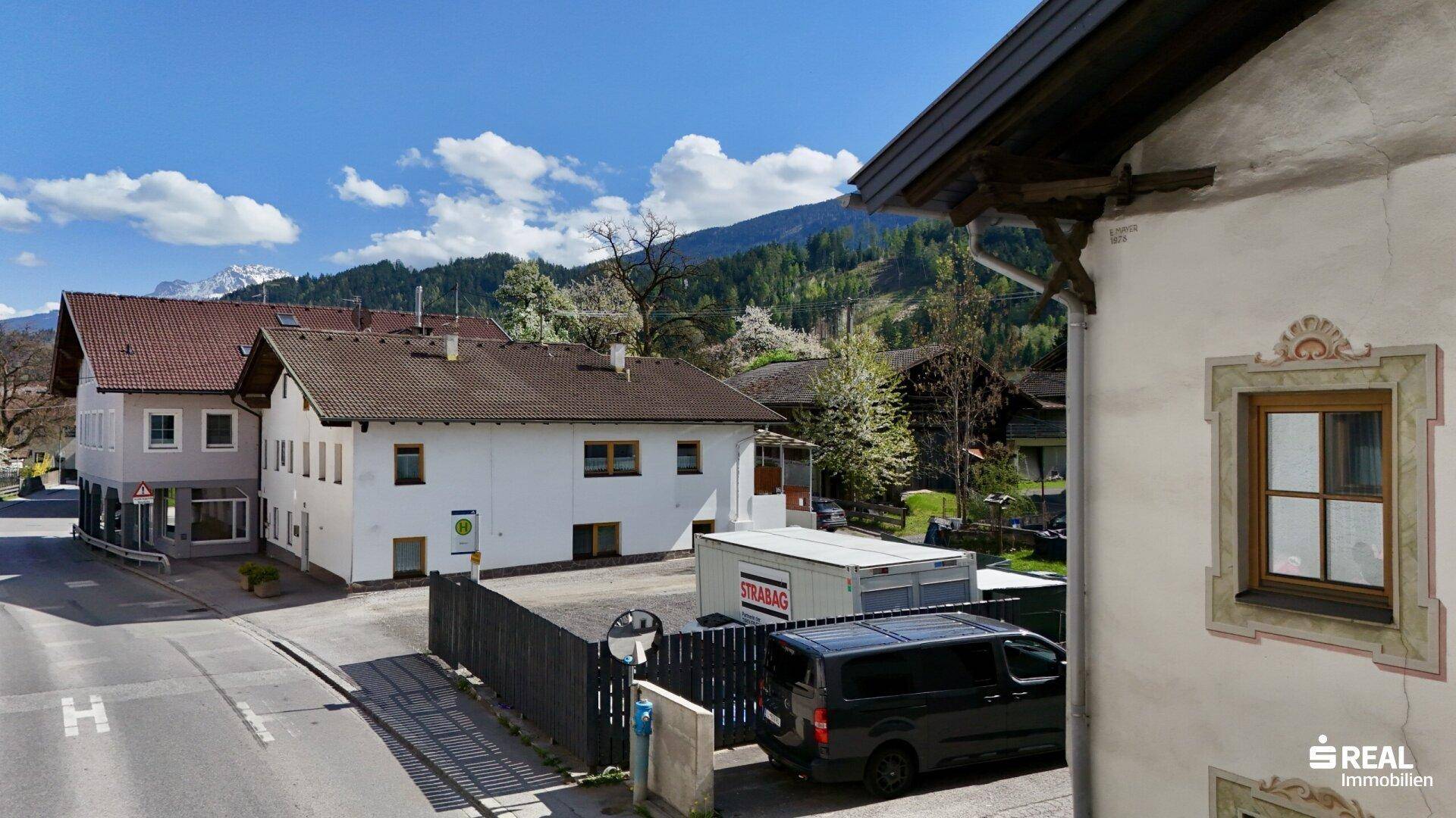 Panoramablick auf die Dorfarchitektur mit traditionellen Häusern und einer malerischen Bergkulisse.