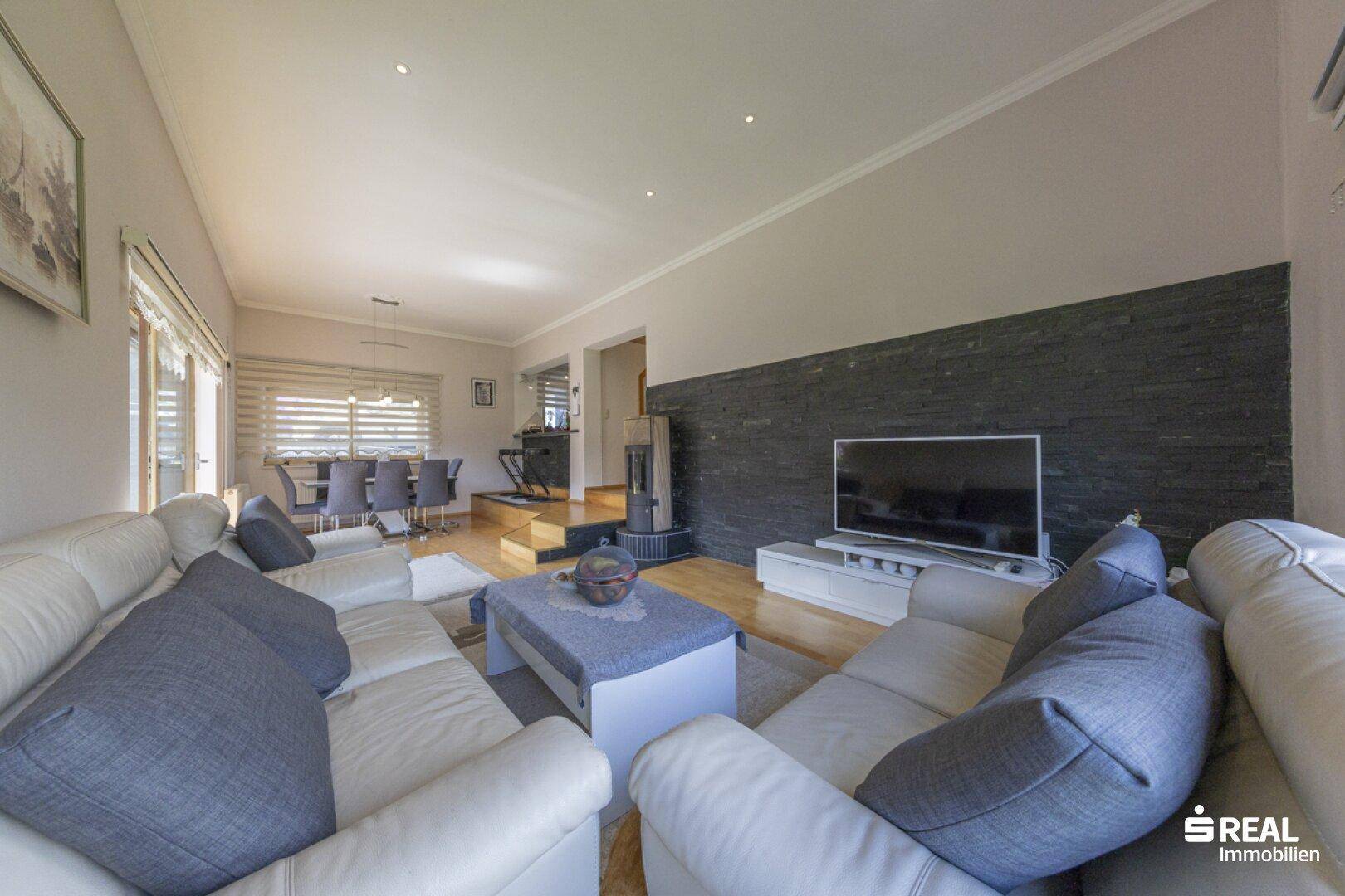 Geräumiges Wohnzimmer mit bequemen Sofas, Holzboden und modernem Kaminofen.