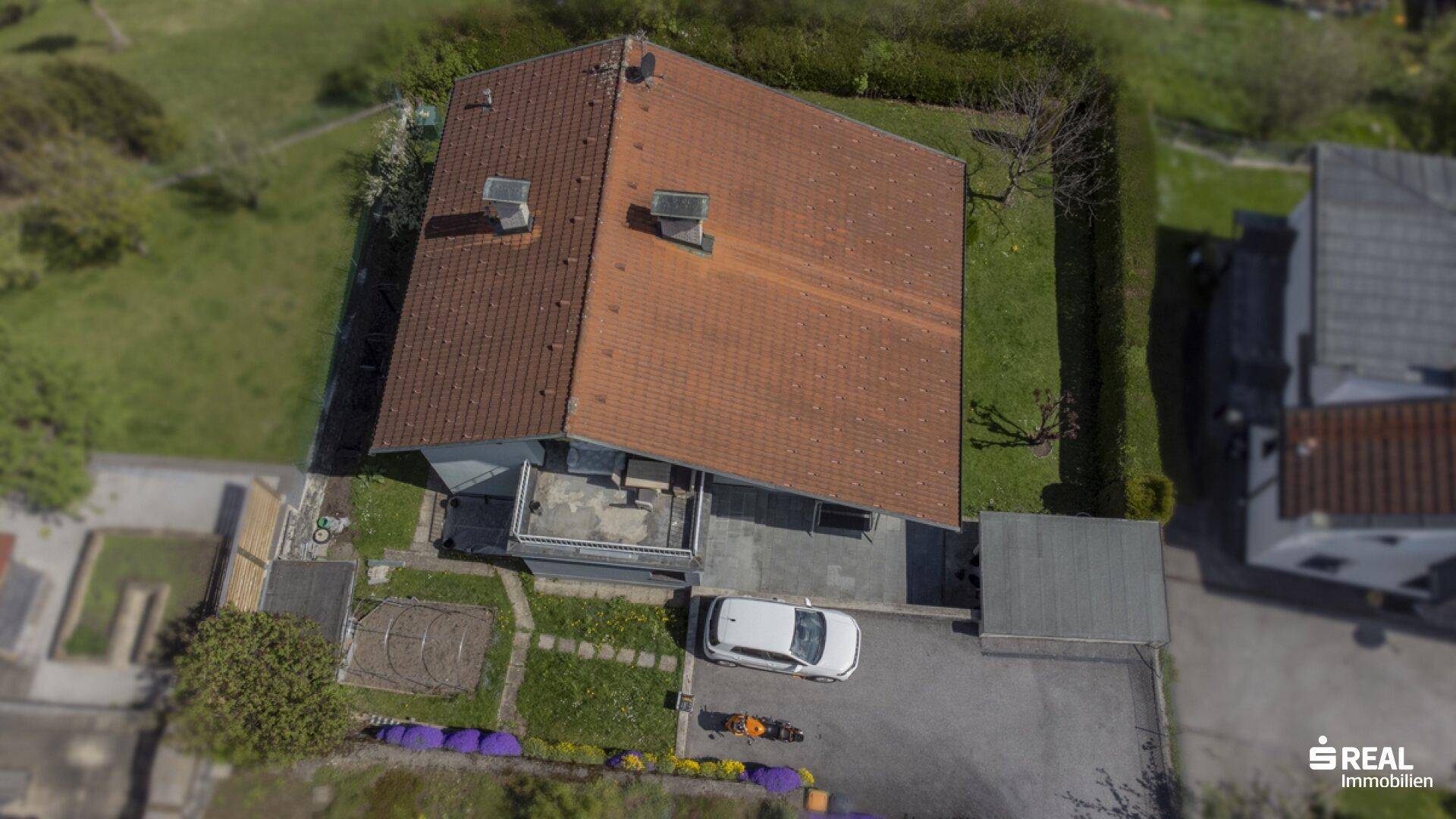 Dachansicht des Hauses mit Ziegeldach, Garten und Stellplatz in ländlicher Umgebung.