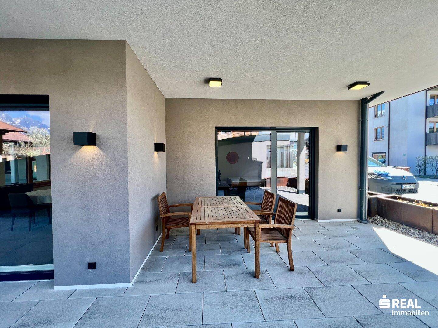 Geräumige Terrasse mit Holztisch und Stühlen, ideal für Mahlzeiten im Freien.