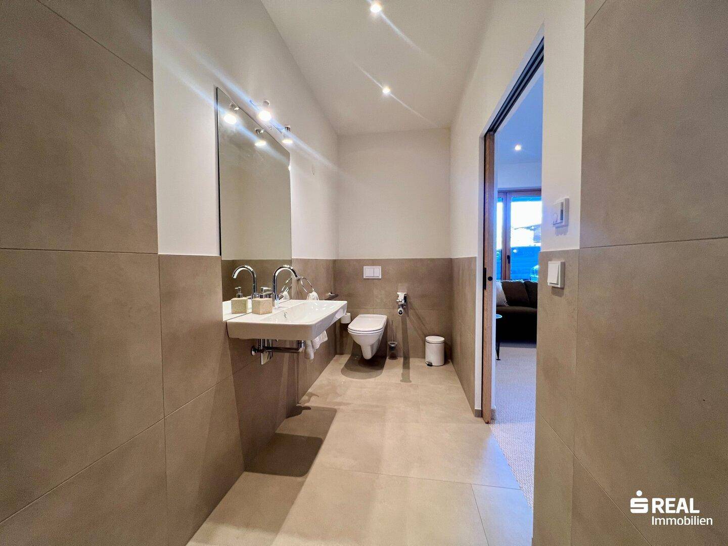 Modernes Badezimmer mit Waschtisch, Spiegel und Wand-WC.