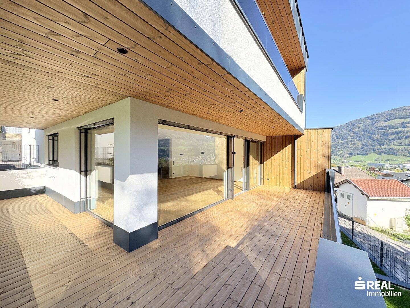 Große Holzterrasse mit moderner Architektur und weitem Blick auf die umliegende Landschaft.