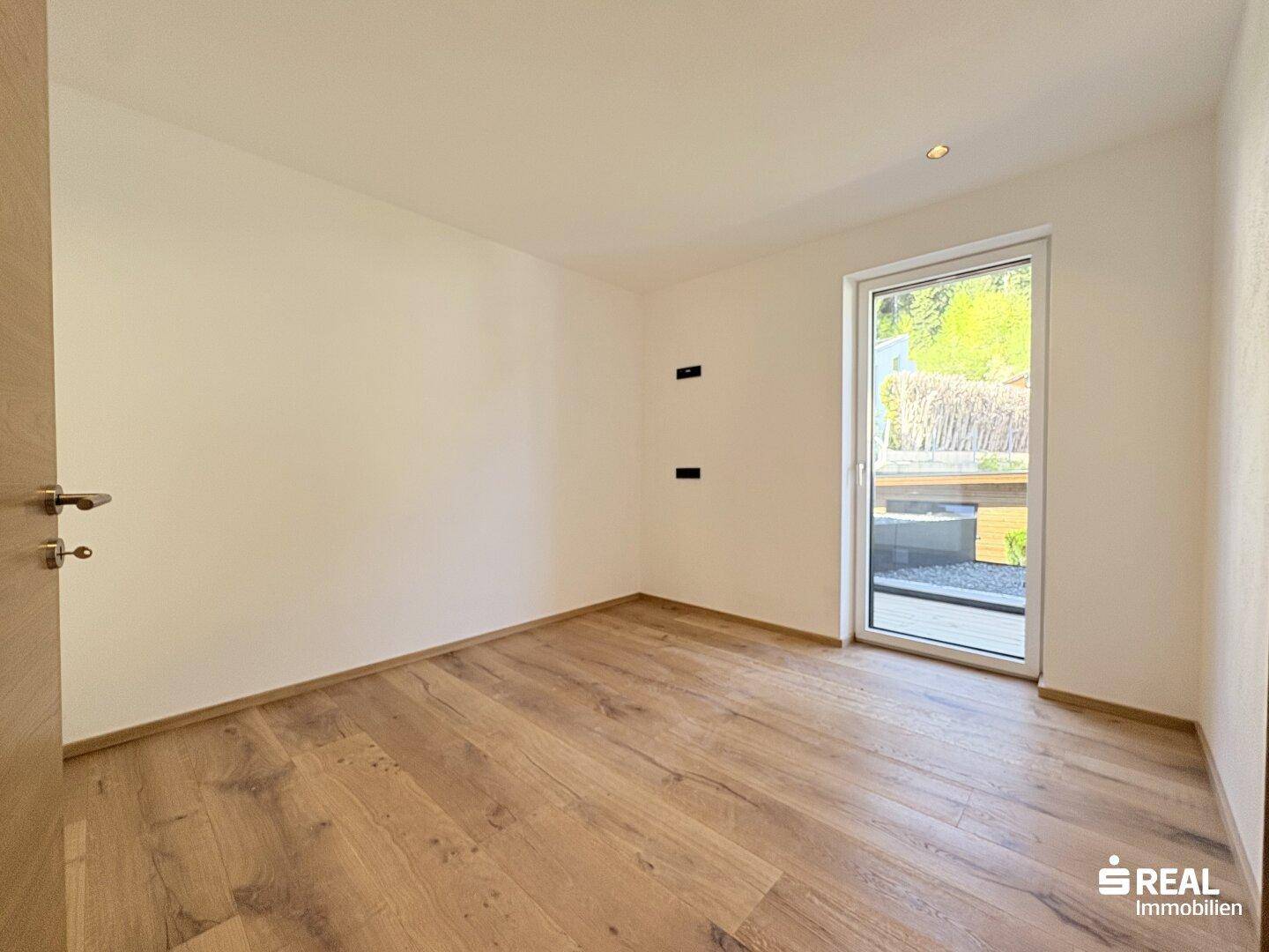 Helles Schlafzimmer mit Holzboden und Zugang zu einem kleinen Außenbereich, ideal für Ruhe.