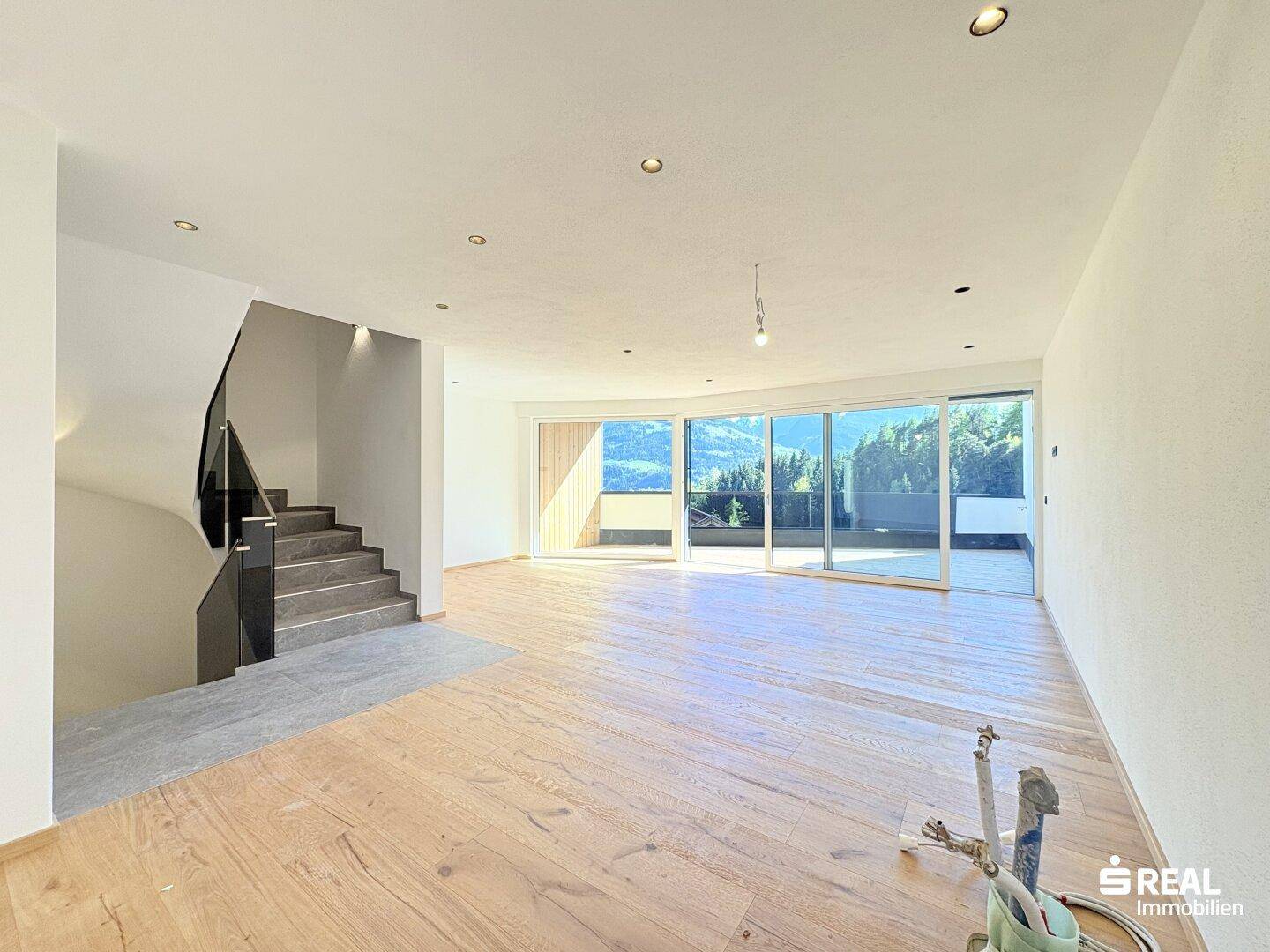 Geräumiger Wohnbereich mit Eichenparkett, moderner Treppe und großen Schiebetüren zum Außenbereich.
