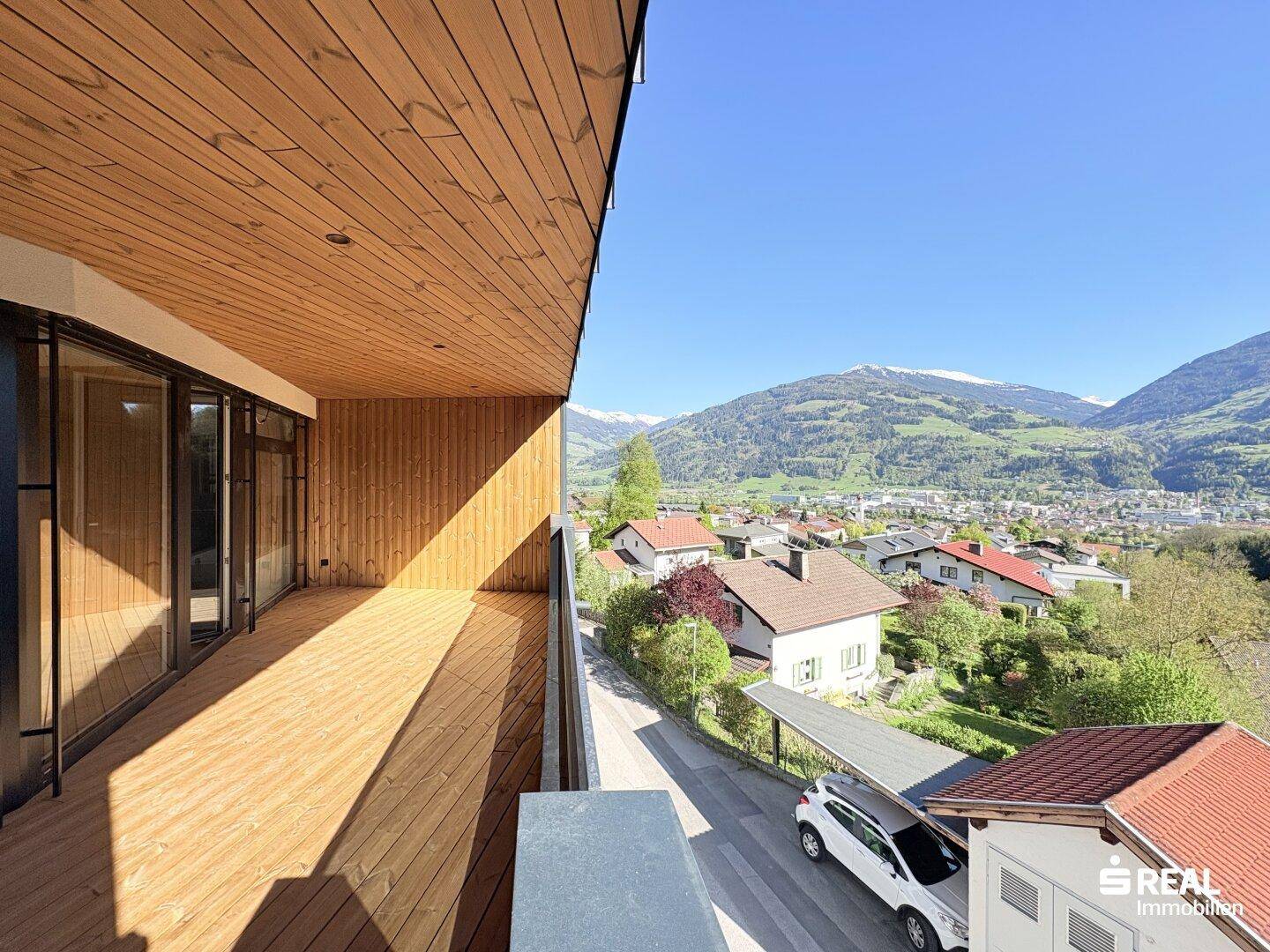 Geräumiger Holzbalkon mit Panoramablick auf die Stadt und die umliegende Berglandschaft.