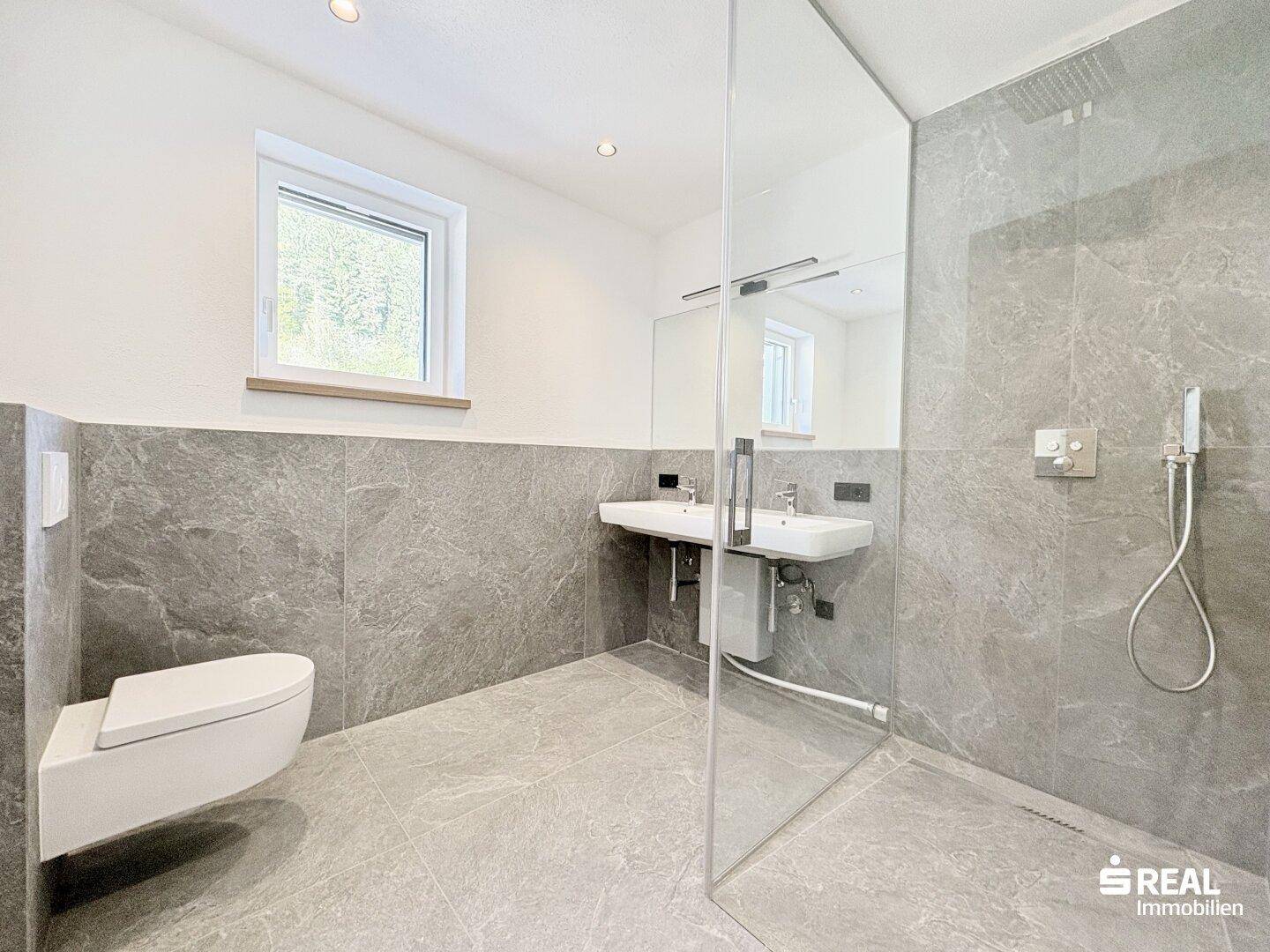 Geräumiges modernes Badezimmer mit begehbarer Dusche, Doppelwaschbecken und Fenster.