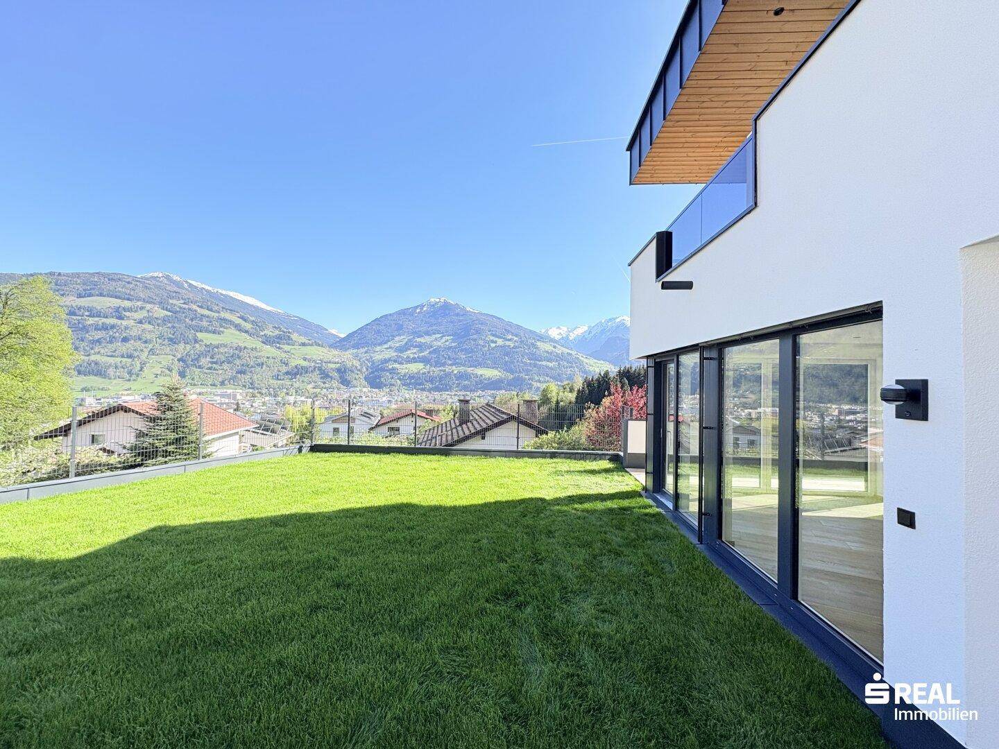 Gepflegte Rasenfläche vor der modernen Fassade mit weitem Bergblick.
