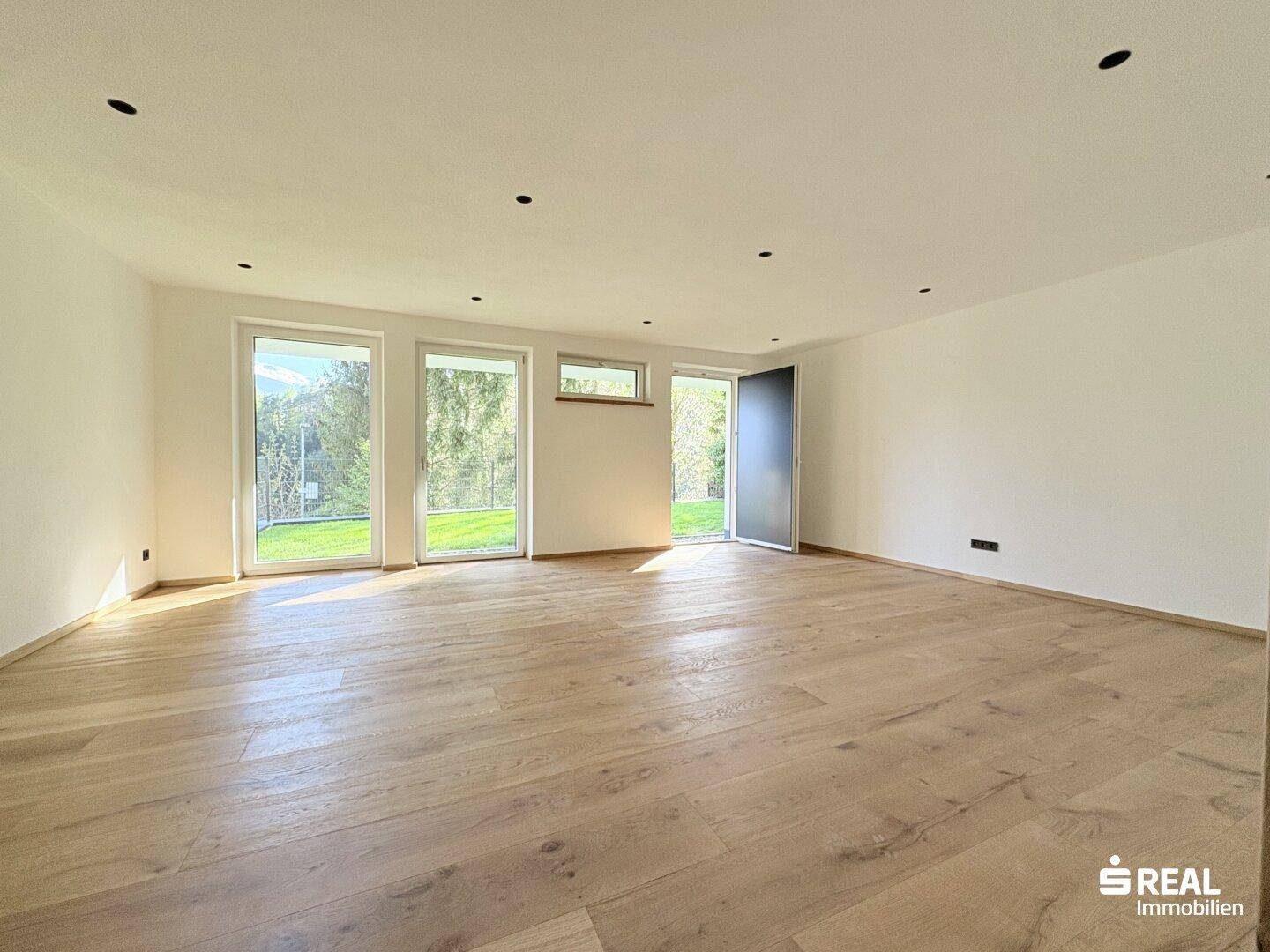 Lichtdurchfluteter Wohnraum mit Holzboden und Zugang zum Garten.