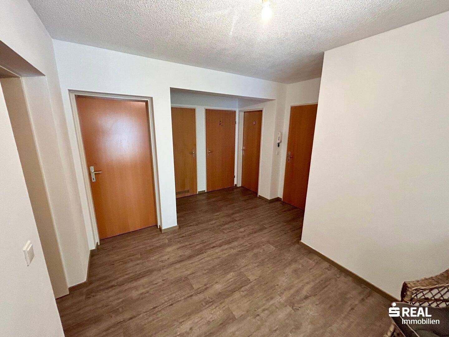 Geräumiger Flur mit mehreren Holztüren und modernem Laminatboden.
