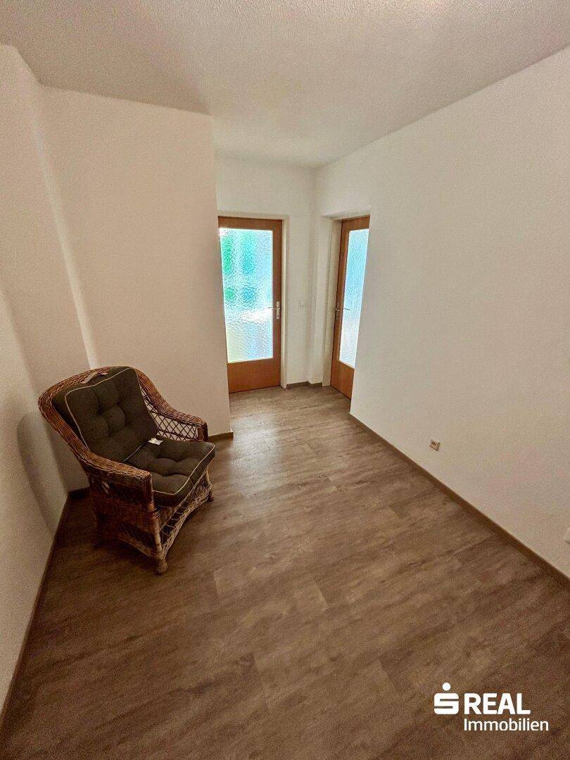 Heller Eingangsbereich mit Laminatboden und einer gemütlichen Korbsessel.