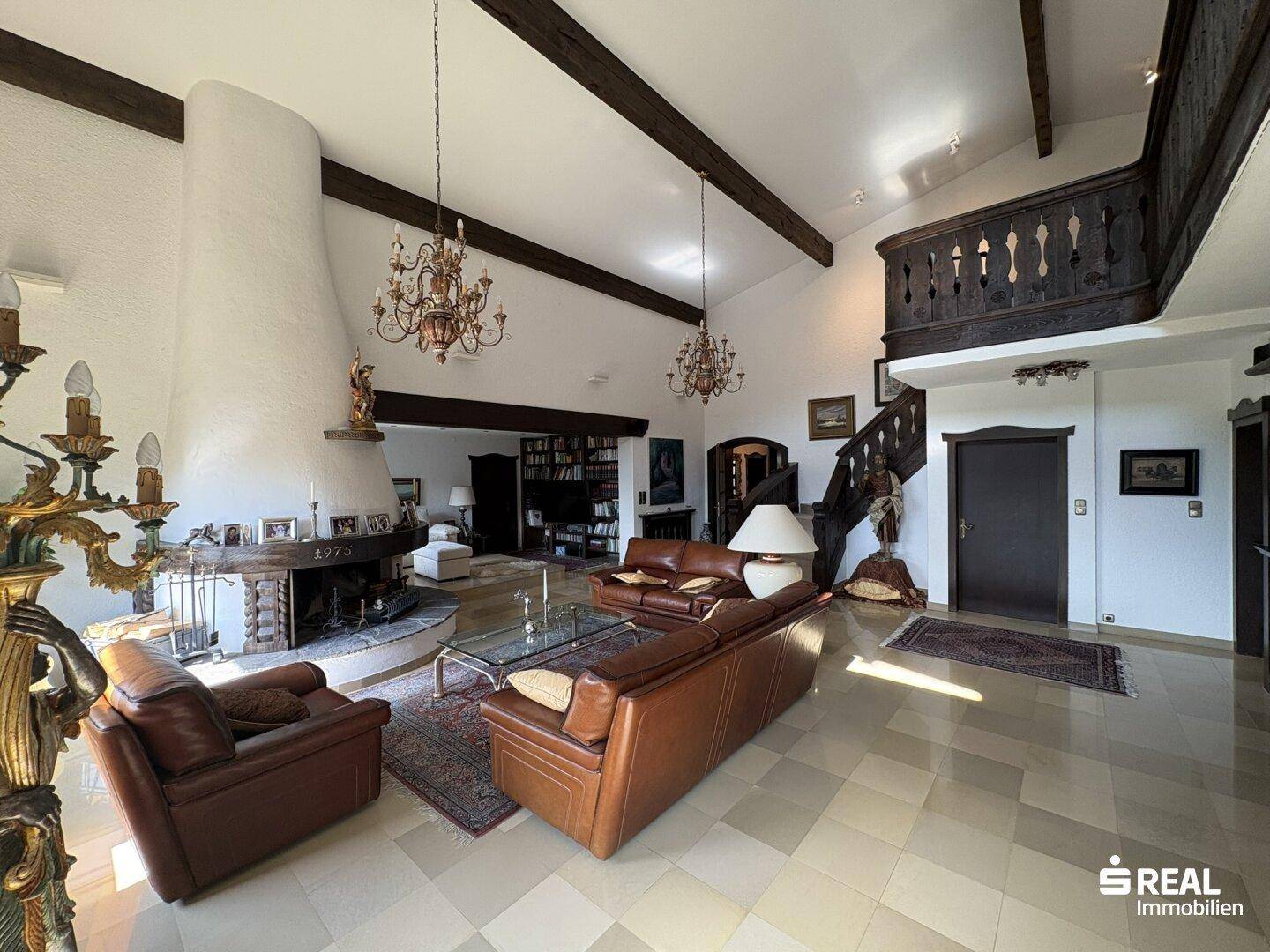Helles Wohnzimmer mit beeindruckendem Kamin, Galerie und traditioneller Holztreppe.