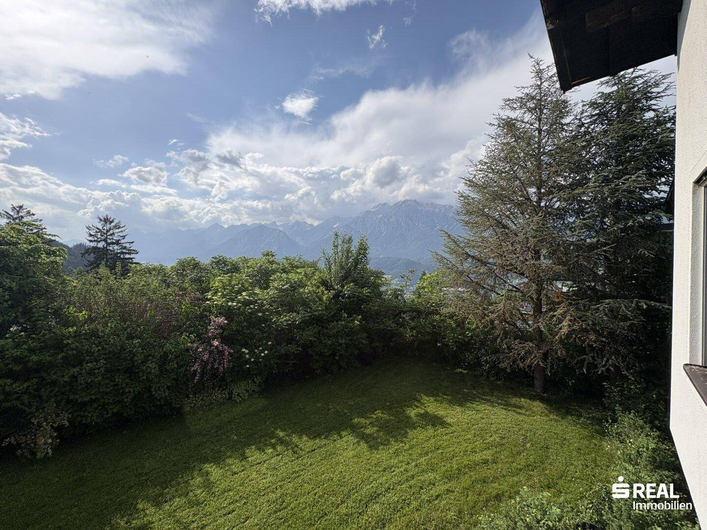 Malerischer Garten mit Rasenfläche und weitem Blick auf die umliegende Berglandschaft.