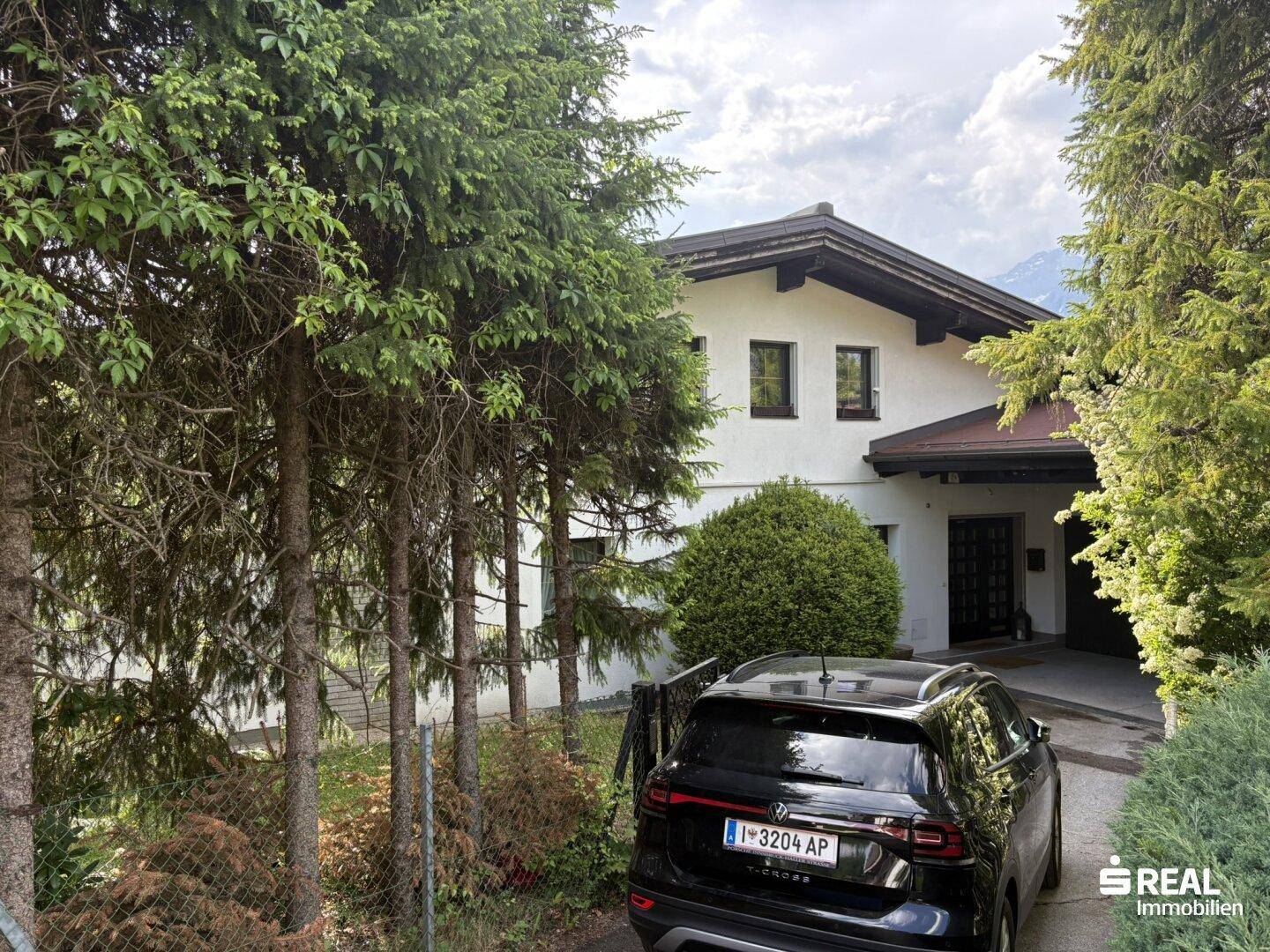 Zufahrt zum Haus mit gepflegter Grünanlage und einem geparkten Auto.