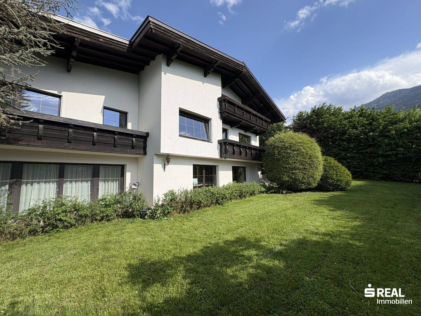 Großer, gepflegter Garten mit Rasenfläche und Blick auf die Hausfassade.