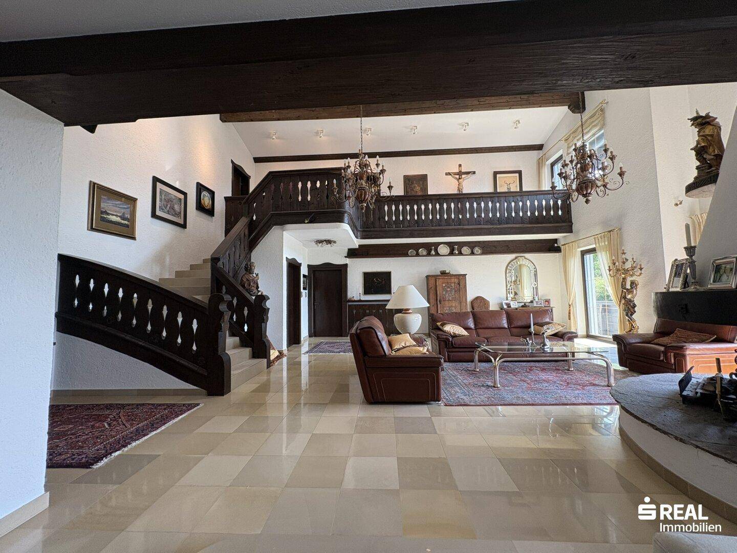 Heller und geräumiger Wohnbereich mit hoher Decke, Ledersofas und einer beeindruckenden Holztreppe.