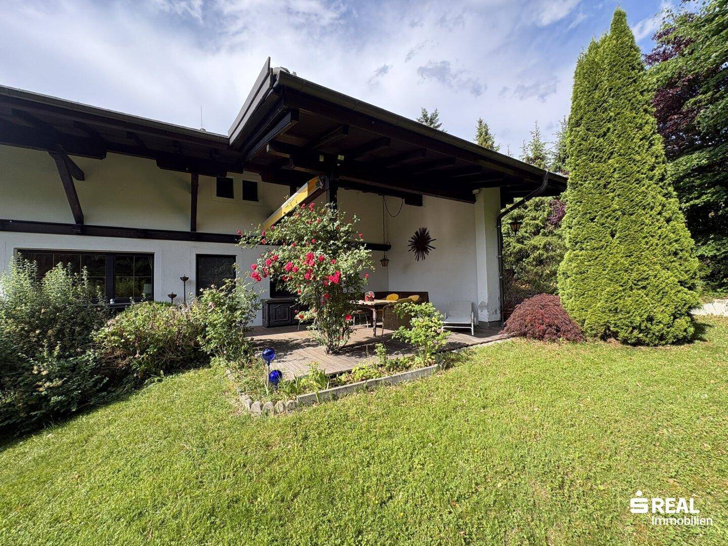 Außenbereich mit Terrasse, Gartenmöbeln und üppiger Bepflanzung.