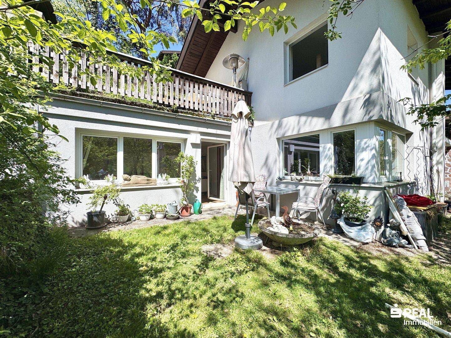 Kleiner Gartenbereich mit Sitzgelegenheiten und Pflanzen vor der Hausfassade im Erdgeschoss.