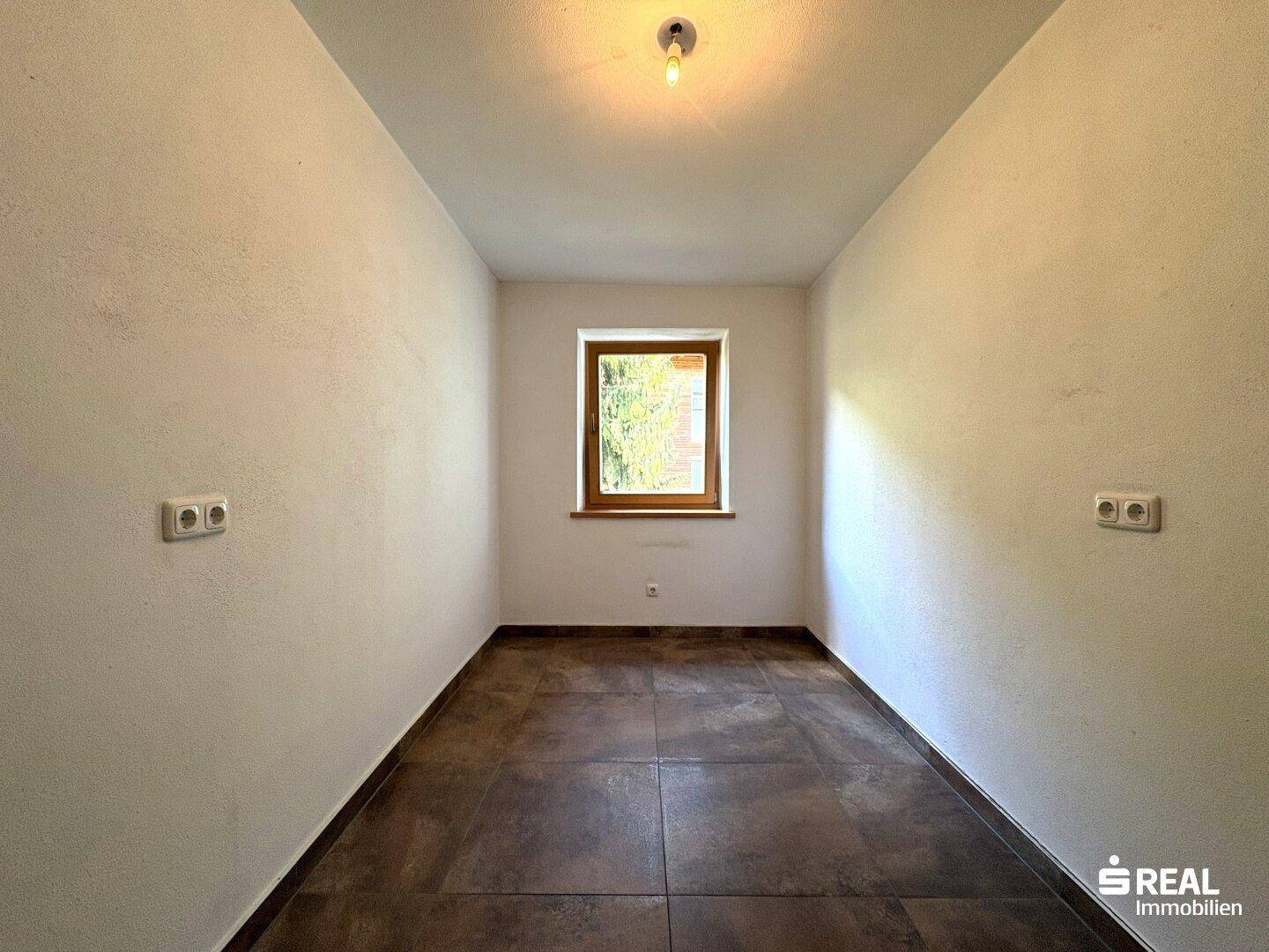Kleiner Raum mit Fliesenboden und einem Fenster, ideal als Abstell- oder Hauswirtschaftsraum.