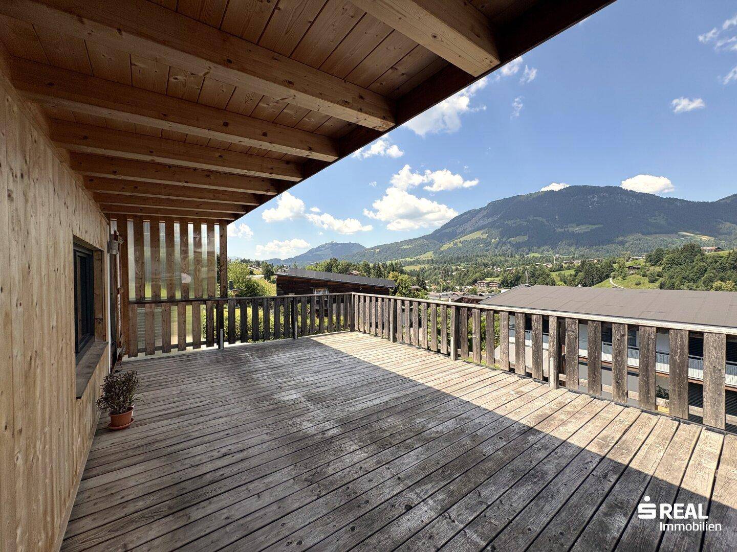 Geräumige Holzterrasse mit weitem Blick auf die umliegende Berglandschaft.