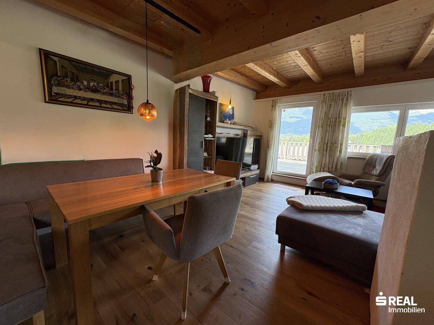 Heller Wohn-Essbereich mit Holzbalkendecke, großen Fenstern und Zugang zur Terrasse.