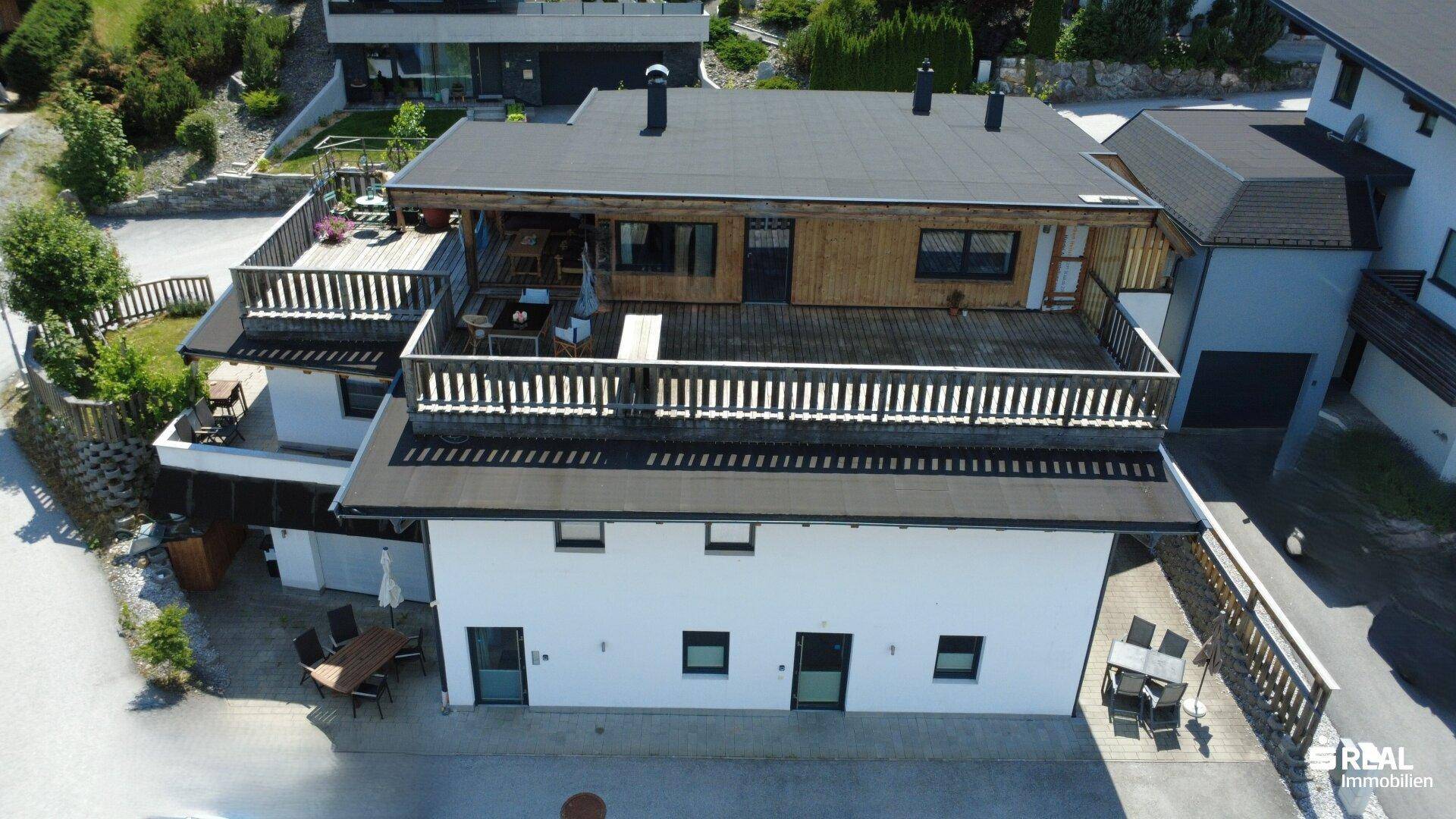 Luftaufnahme des Anwesens mit mehreren Terrassen und moderner Architektur in grüner Umgebung.