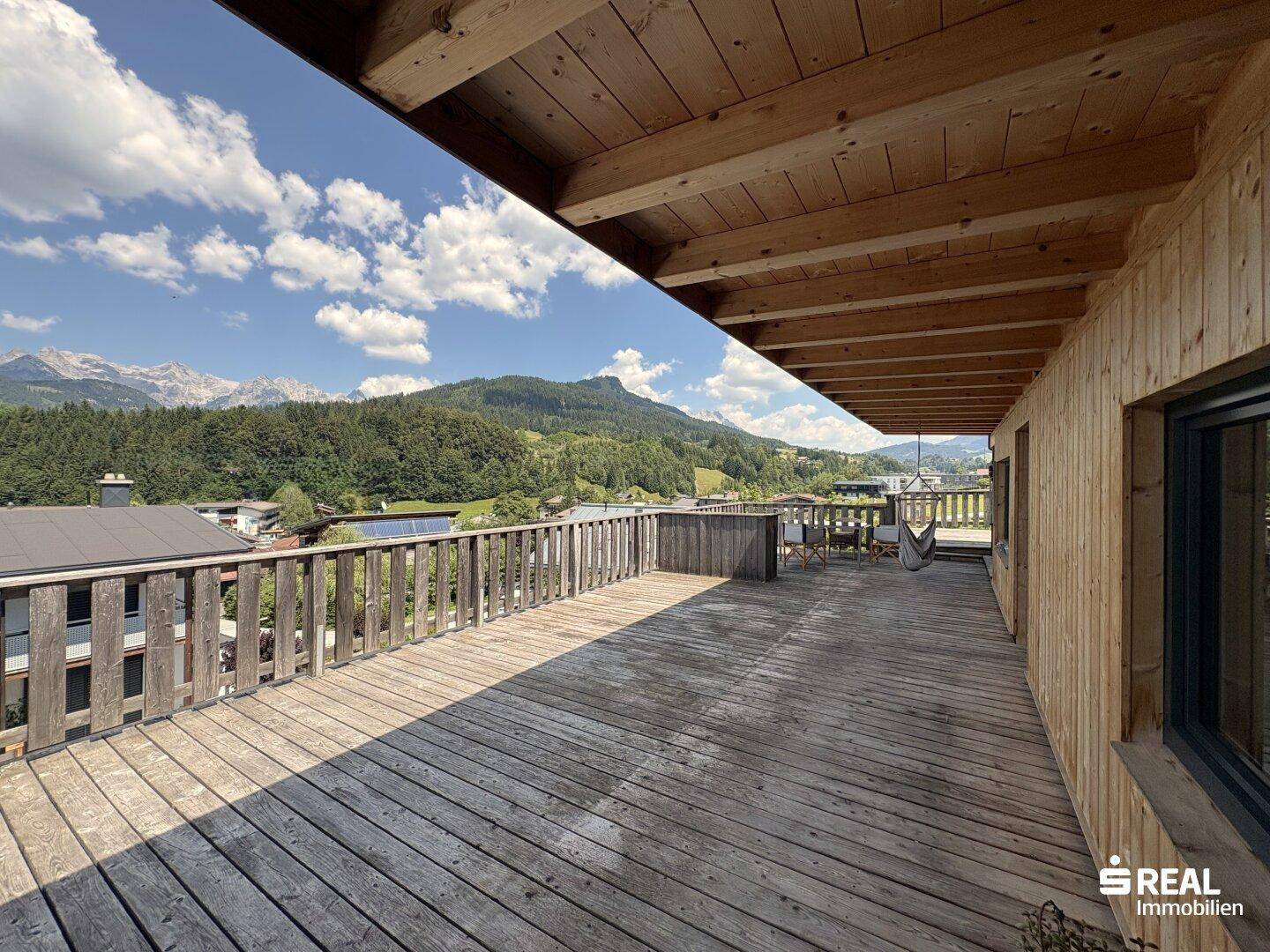 Große Holzterrasse mit Panoramablick auf Berge und einen See in der Ferne.