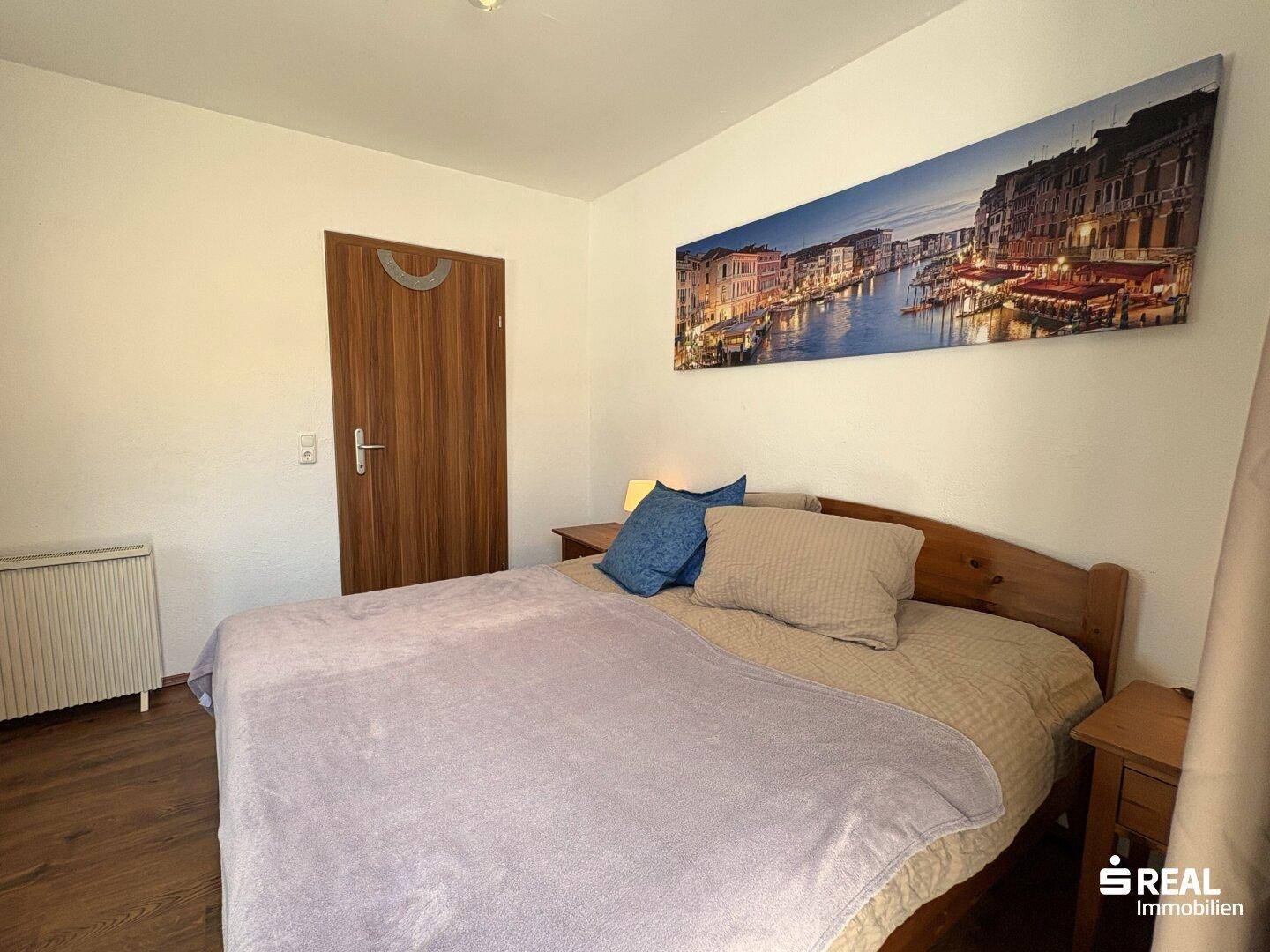 Gemütliches Schlafzimmer mit Holzbett, Nachttischen und großem Wandbild.