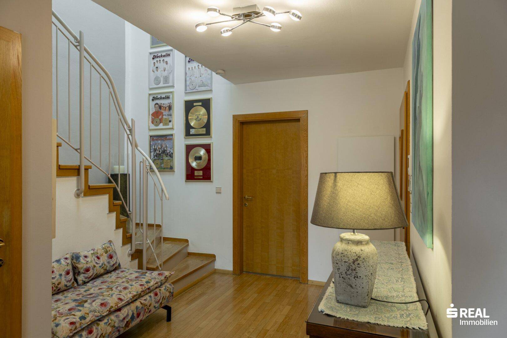 Heller Flur mit Holztreppe, Parkettboden und dekorativen Bildern an der Wand, einladend gestaltet.