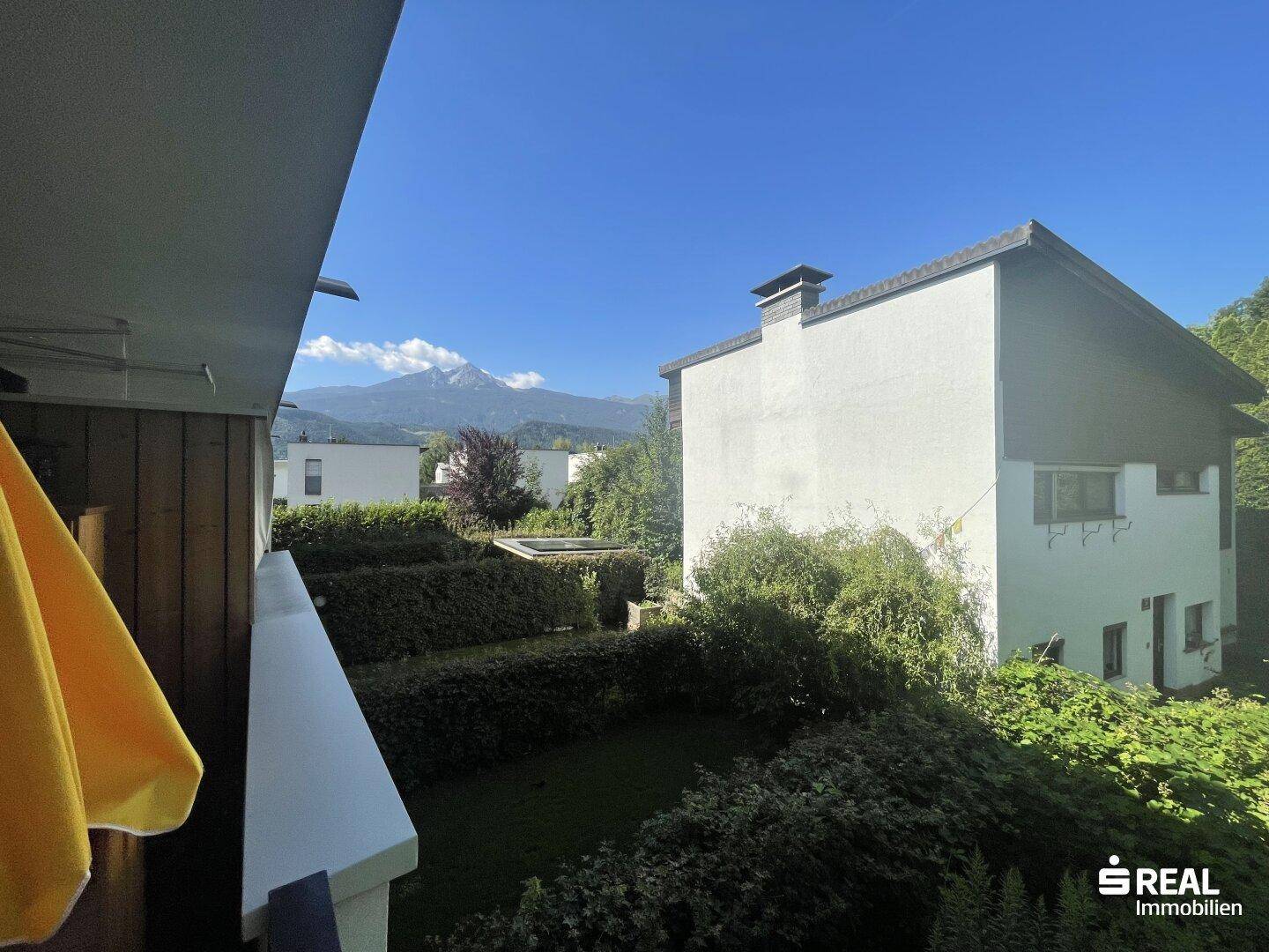 Sonniger Balkon mit Bergblick und grüner Umgebung, ideal zum Entspannen.