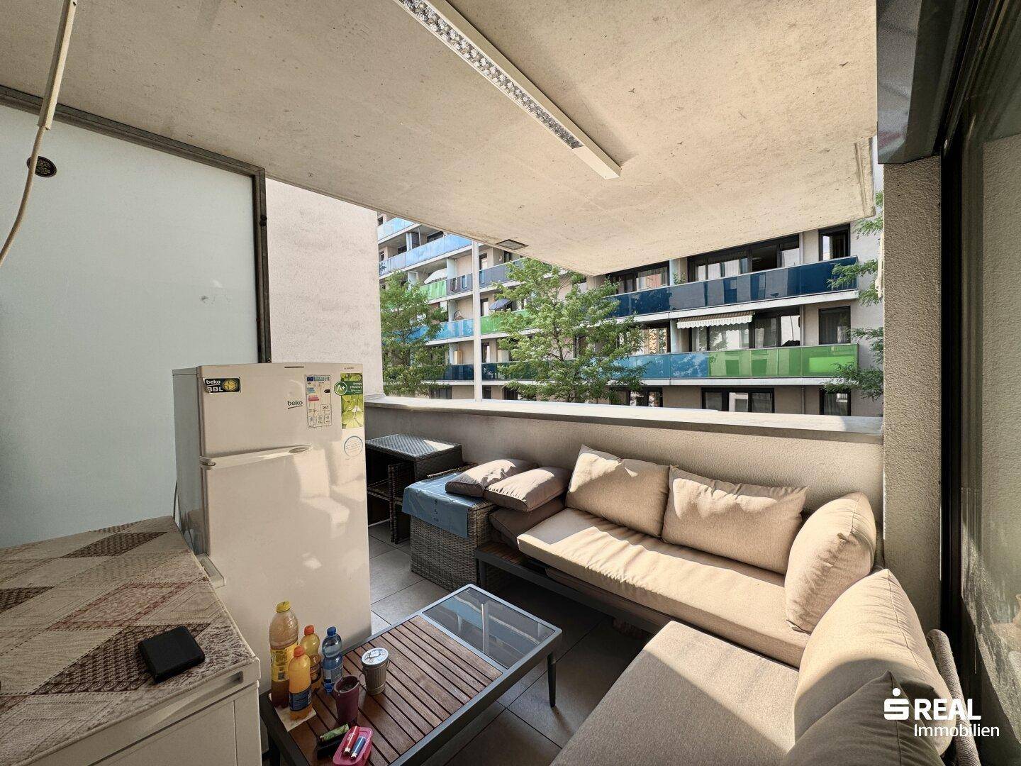 Möblierter Balkon mit Blick auf andere Wohngebäude und viel Grün.