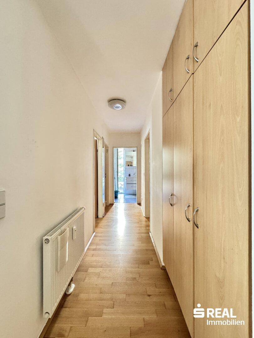 Langer Flur mit Einbauschränken und Holzboden, der zu weiteren Räumen führt.