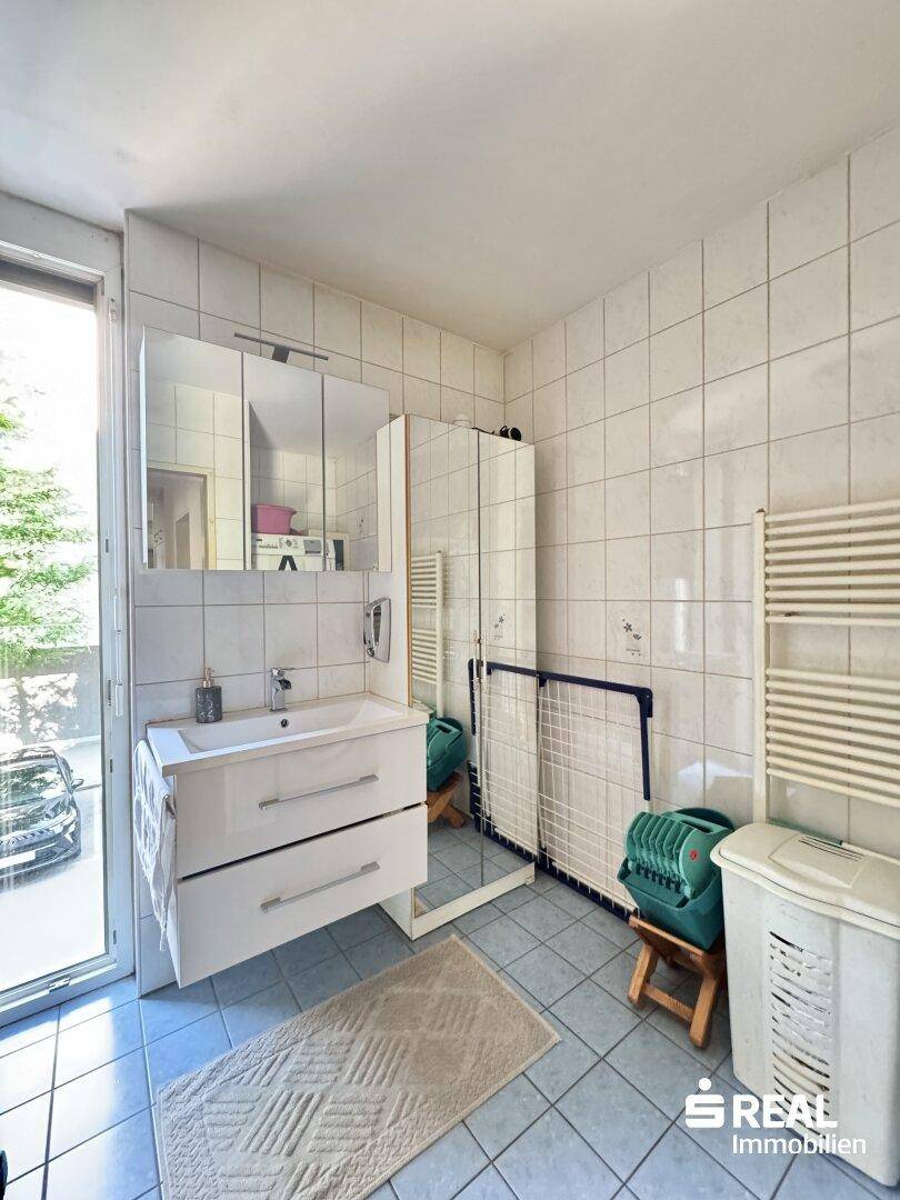 Badezimmer mit Waschbecken, Spiegelschrank, Fliesenboden und Fenster.