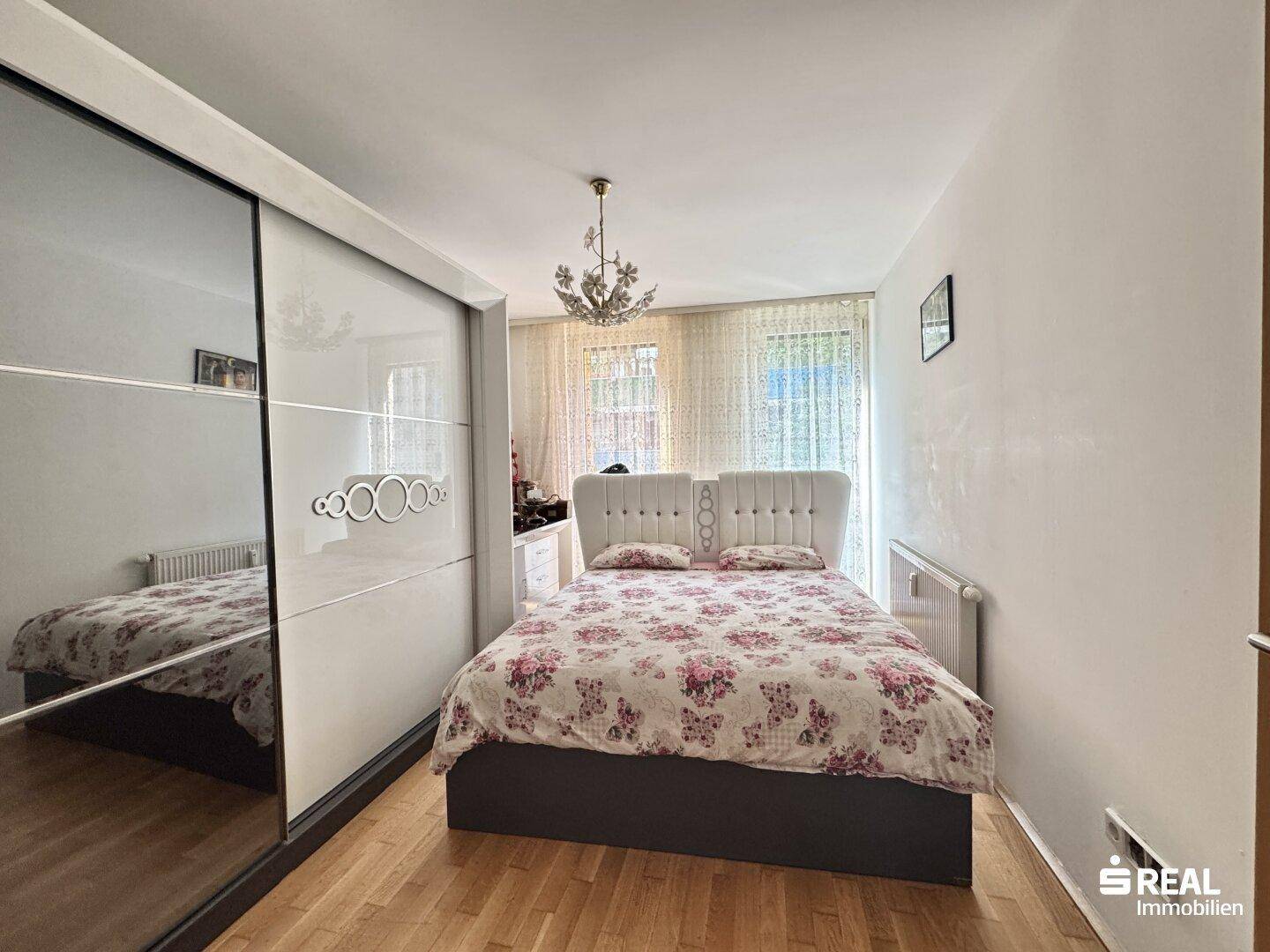 Schlafzimmer mit Doppelbett, Spiegelschiebetürenschrank und Holzboden.