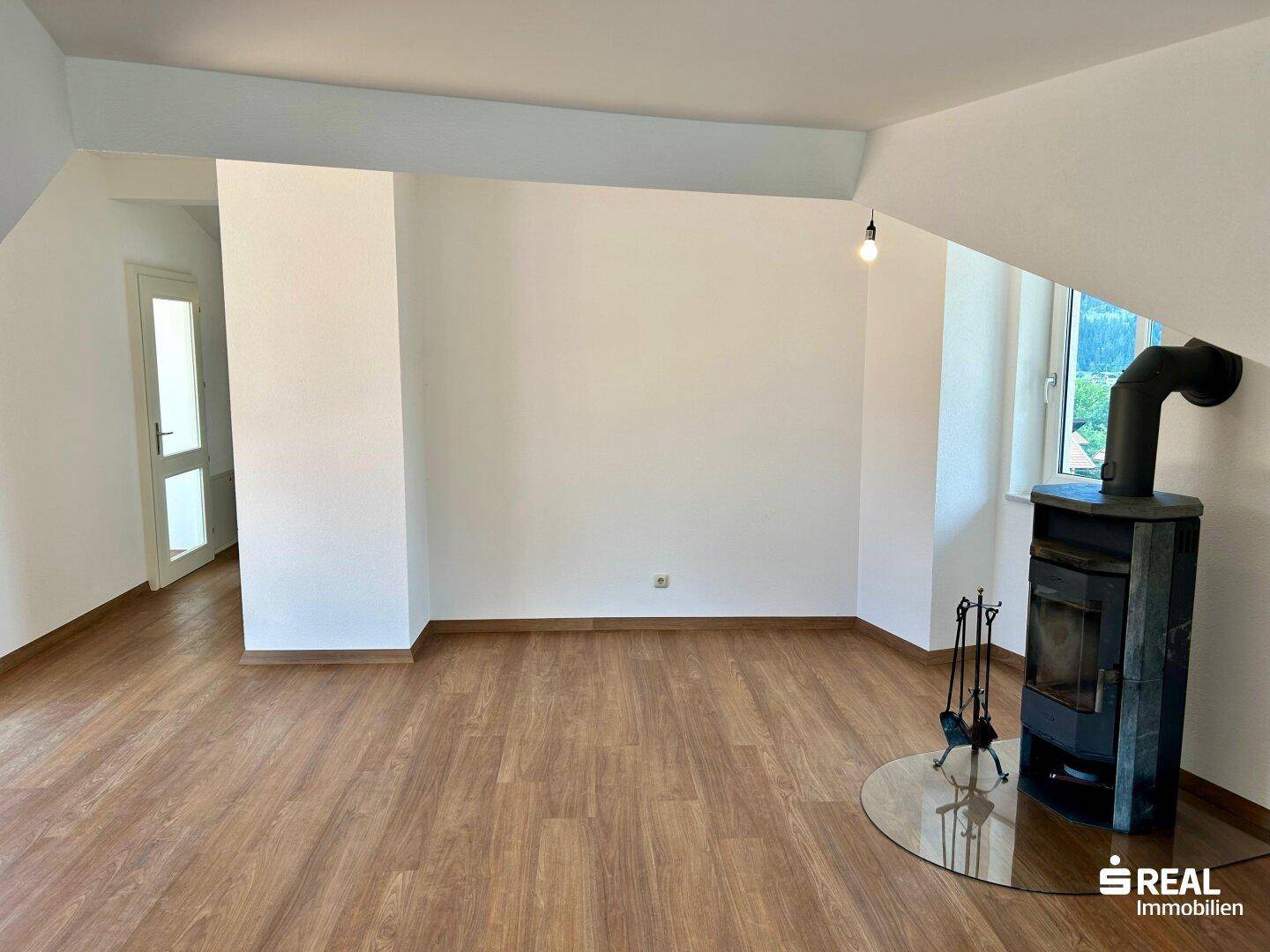 Gemütlicher Wohnbereich mit Holzboden und einem modernen Holzofen für zusätzliche Wärme.