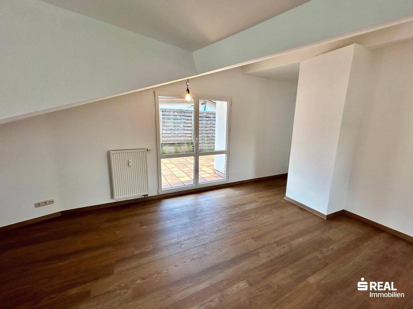 Lichtdurchfluteter Wohnbereich mit Zugang zur Außenterrasse durch große Fenstertüren.