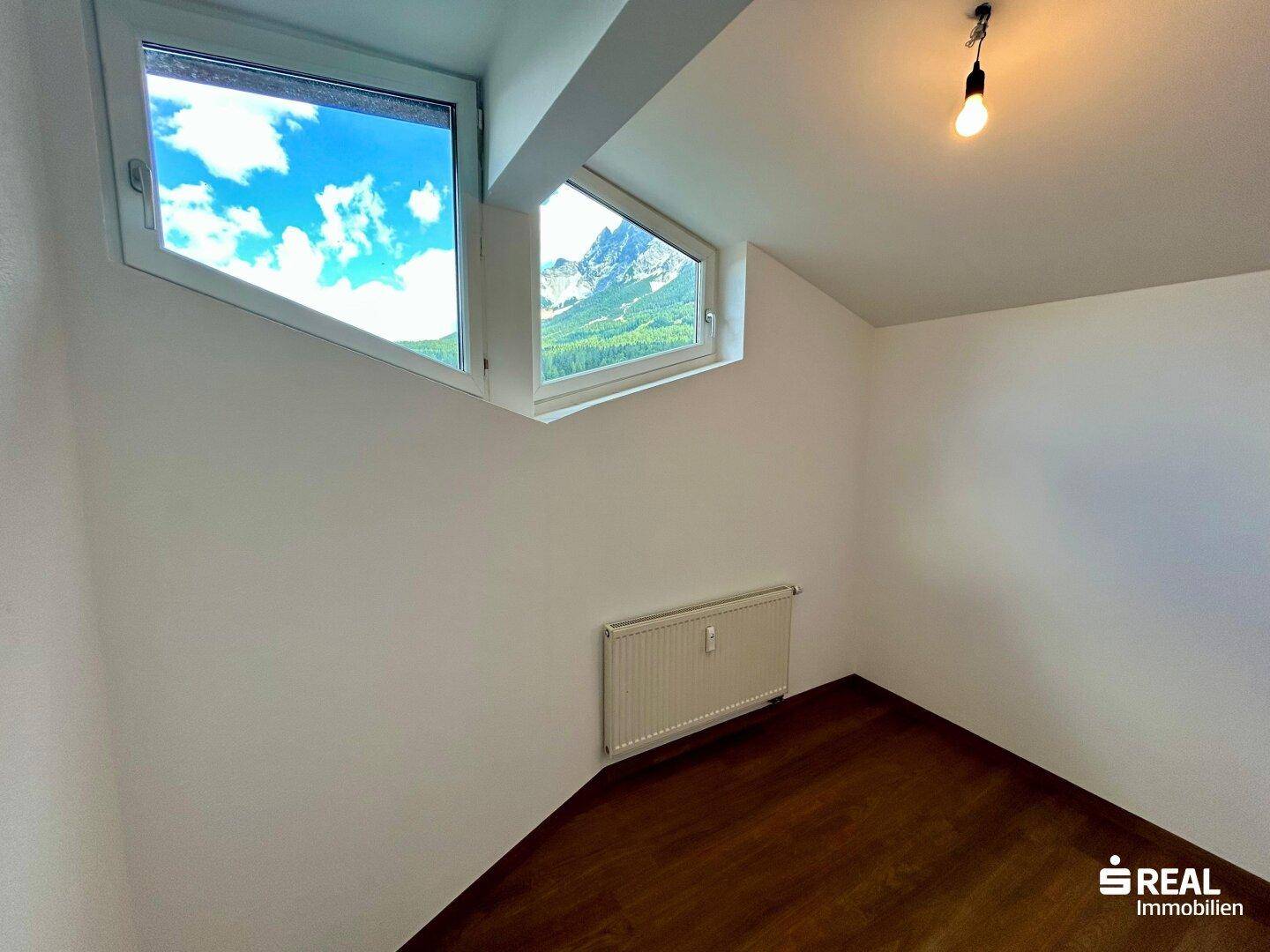 Schlafzimmer mit Laminatboden und einem atemberaubenden Blick auf die umliegenden Berge.