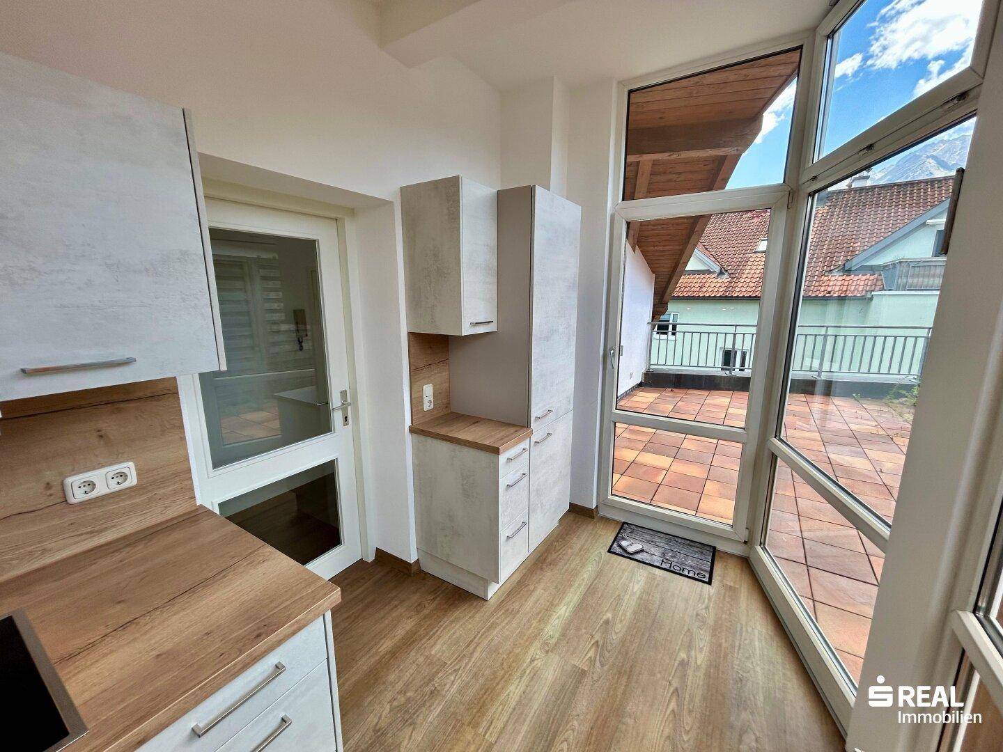 Helle Küche mit modernen Geräten und direktem Zugang zu einer sonnigen Dachterrasse.