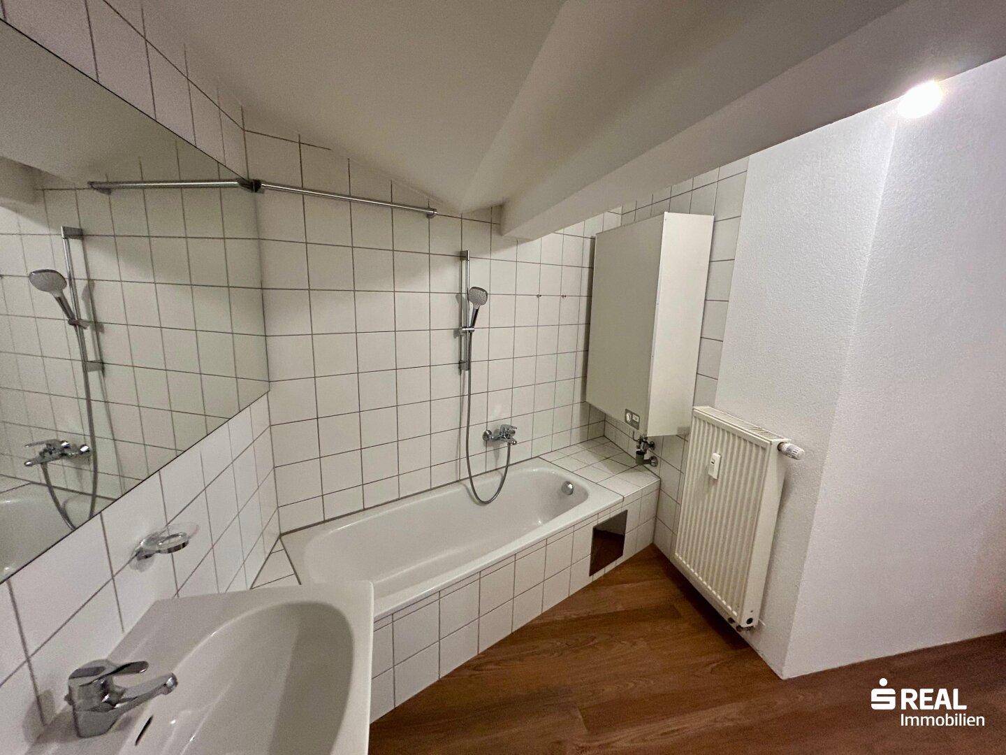 Badezimmer mit Badewanne, Duschfunktion und weißen Wandfliesen, bereit zur Nutzung.