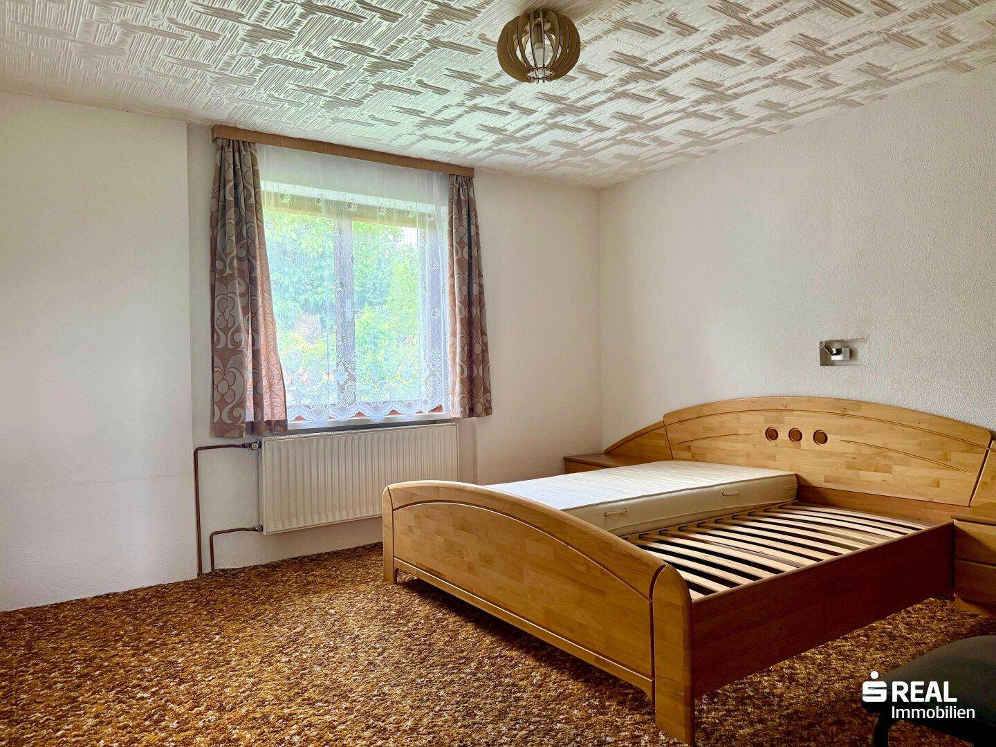 Schlafzimmer mit Holzbett, Teppichboden und gemusterter Decke im traditionellen Stil.
