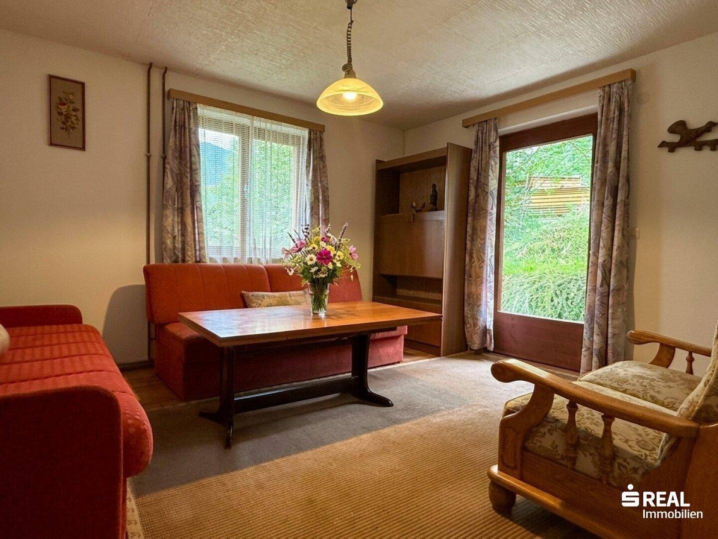 Gemütliches Wohnzimmer mit Sofa, Couchtisch und Zugang zum Gartenbereich.
